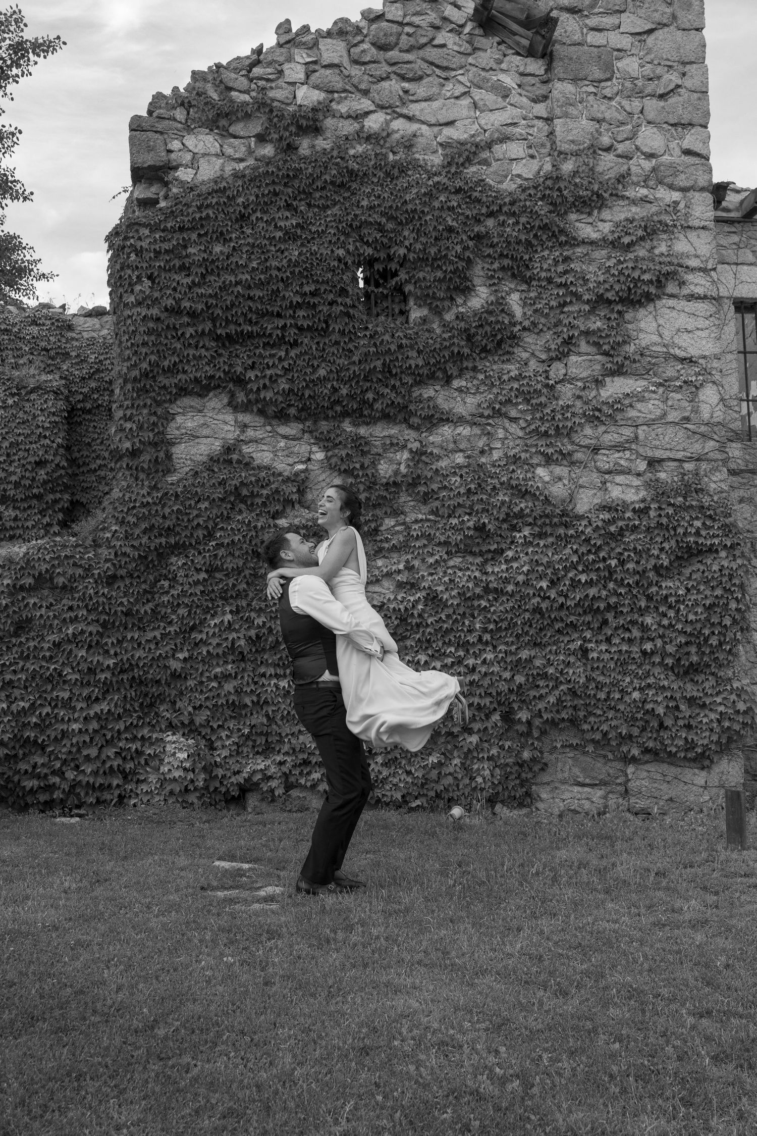 Couple dancing and spinning near an old stone wall covered in ivy.