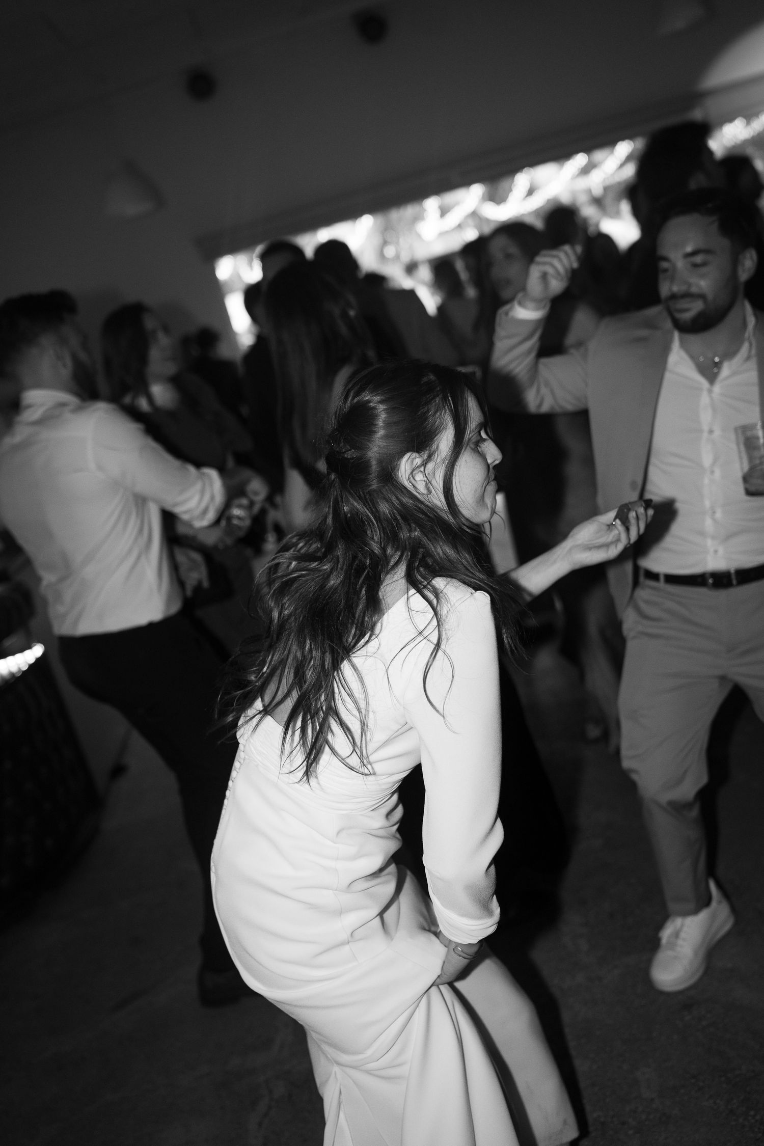 People moving energetically on a dimly lit dance floor at a celebration.