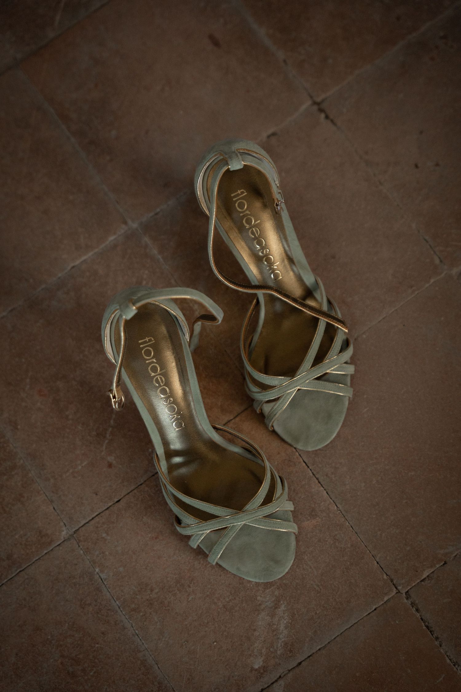 Mint green strappy sandals on terracotta floor.