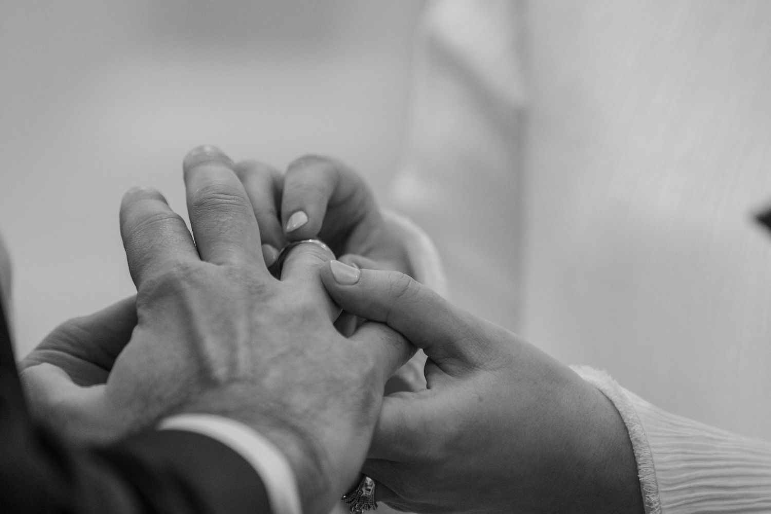 Close-up of hands intertwined in black and white emotional wedding moment.