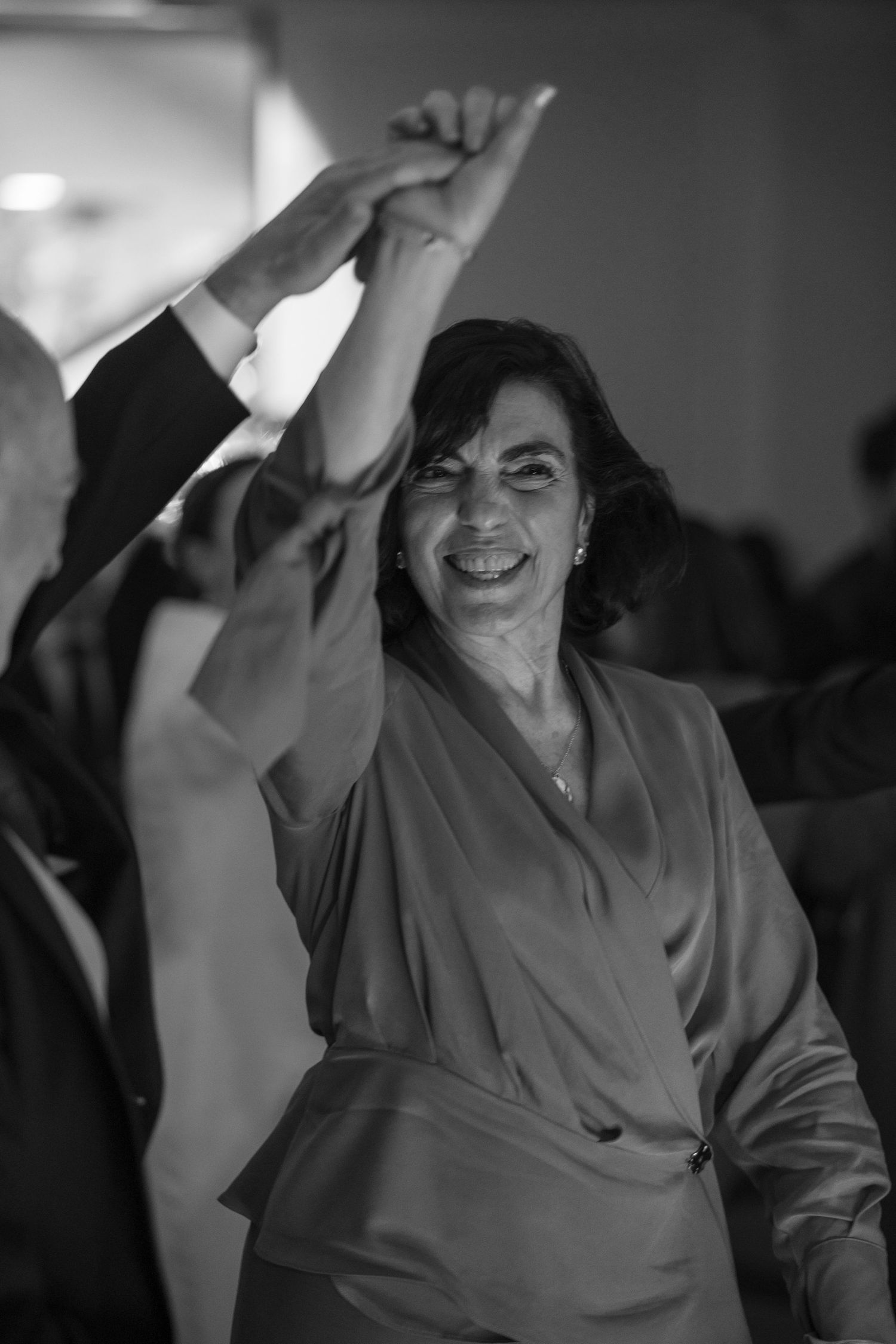 Person in gray dress dancing with raised arms at a celebration.