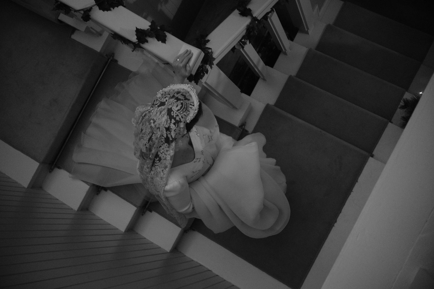 Overhead view of someone in white dress descending ornate staircase.