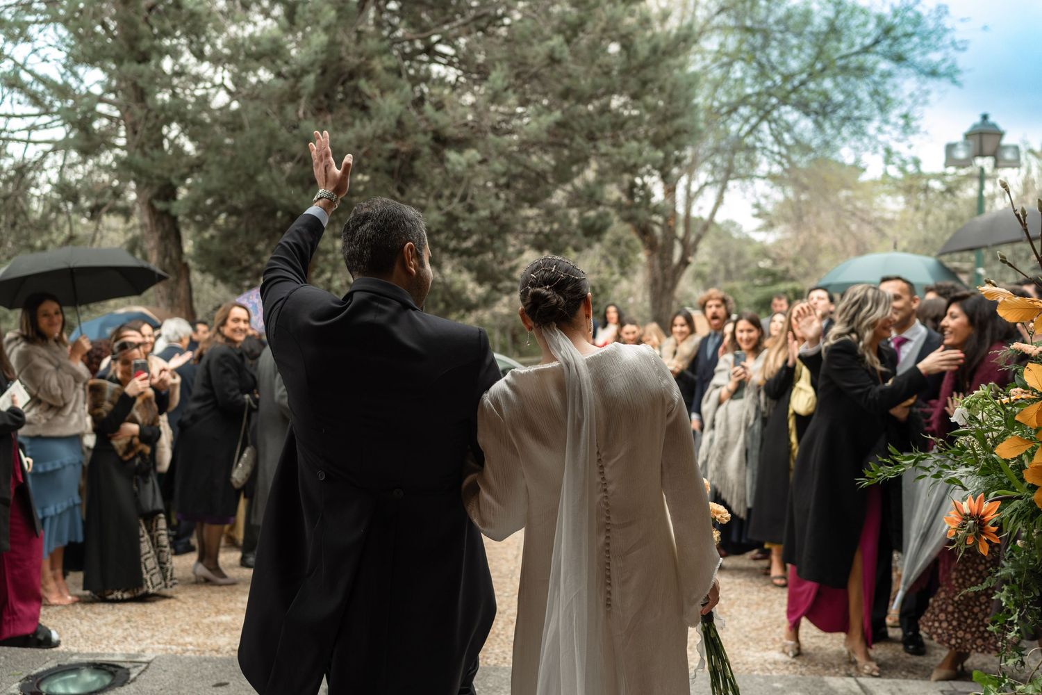 Wedding guests cheer as the couple waves during their outdoor celebration.