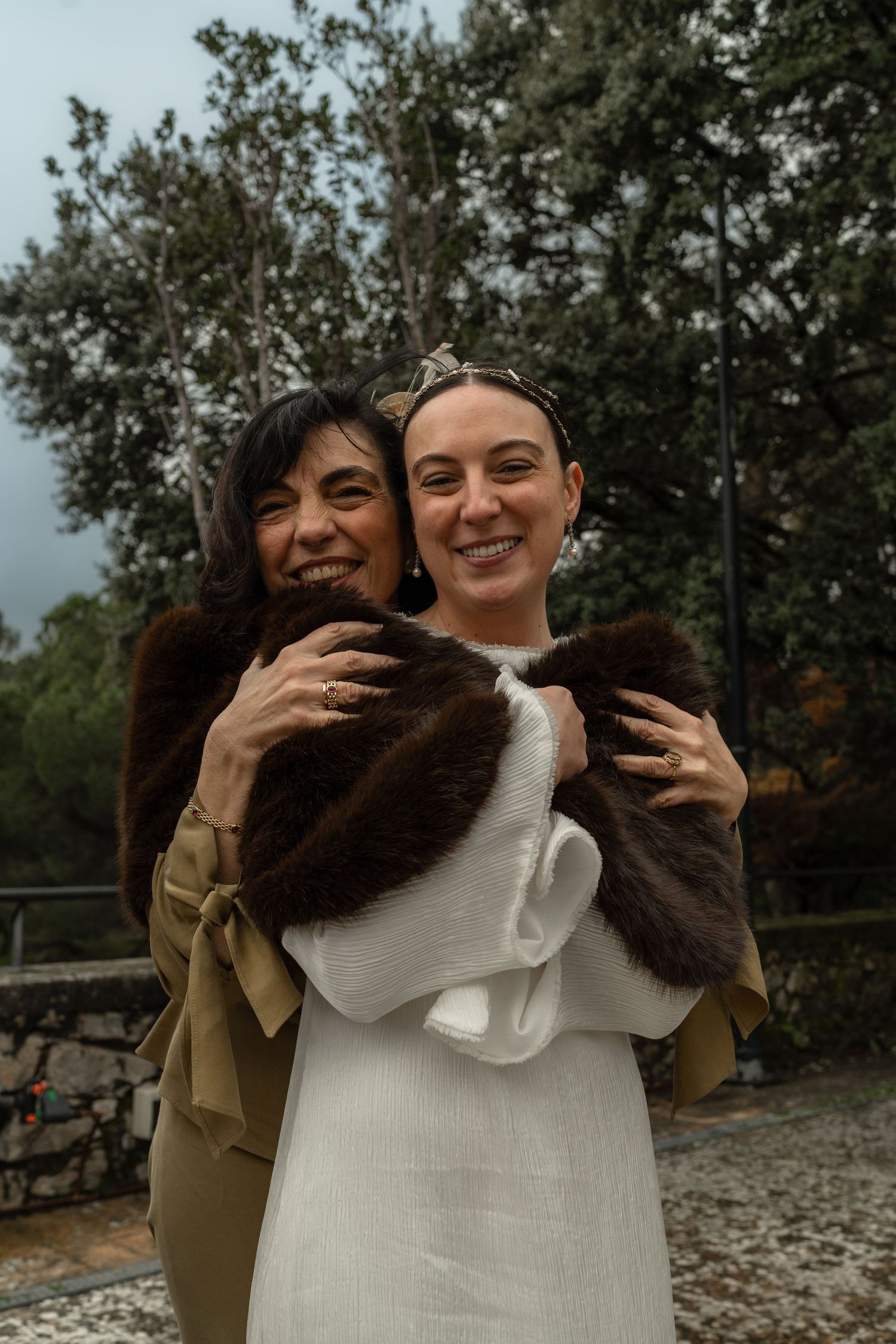 Two people embracing and laughing outdoors on an overcast day.