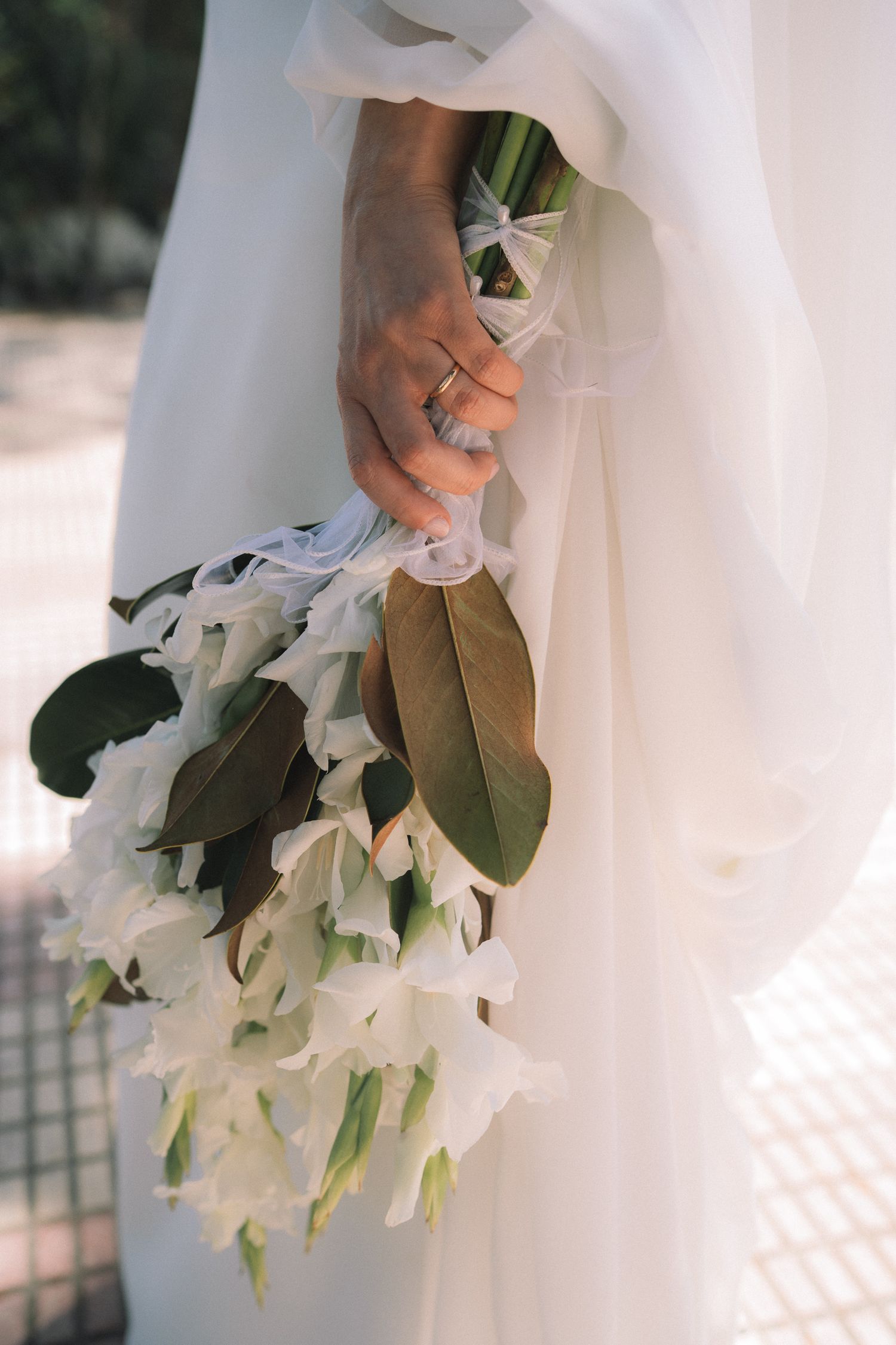 Close-up of a white wedding bouquet with delicate flowers and green foliage.