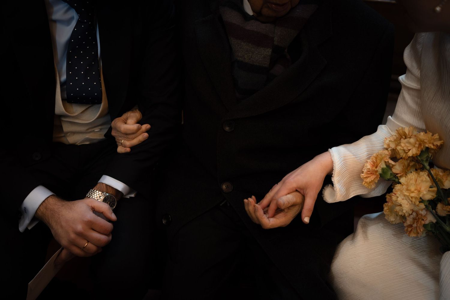 Wedding candid moments captured in dark lighting with floral bouquet details.