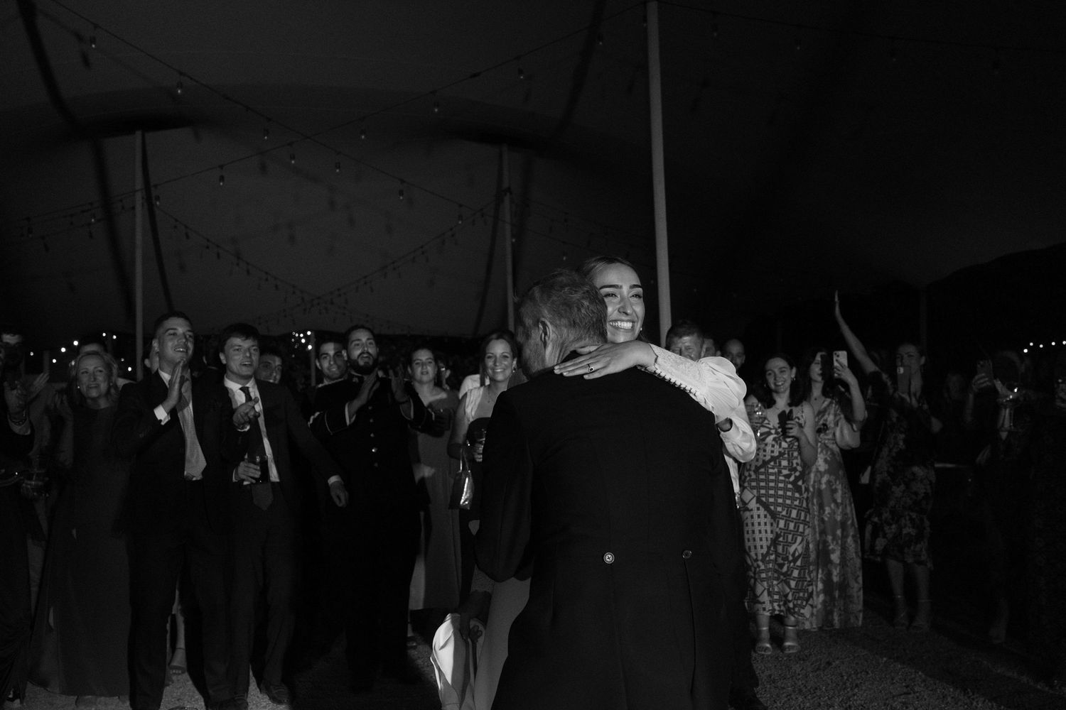 Intimate black and white moment of dancers embracing at a wedding reception.
