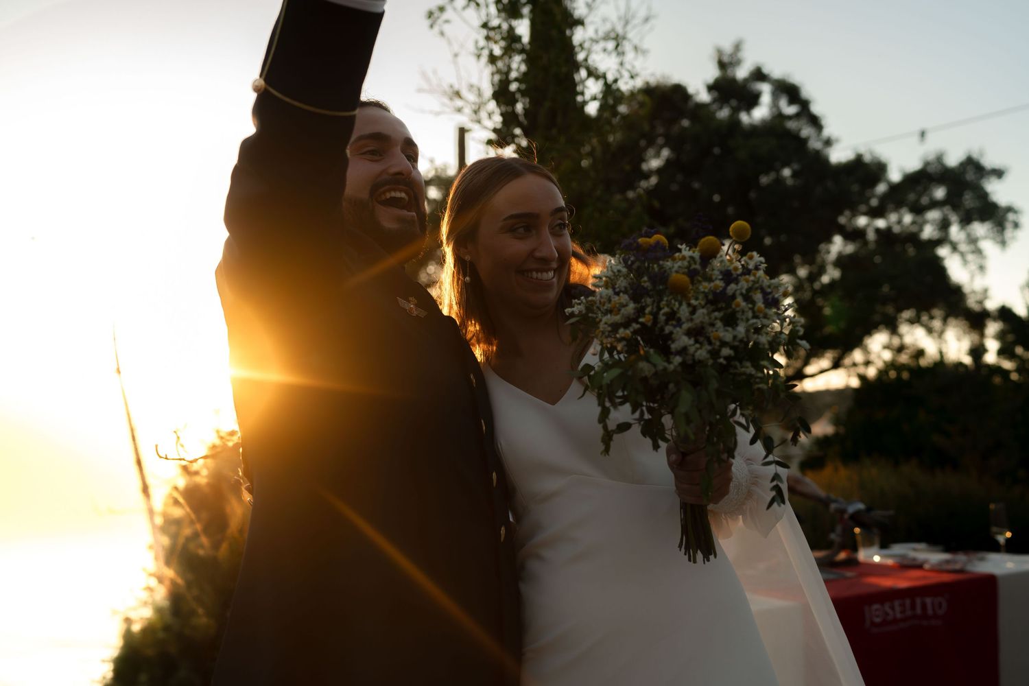 Wedding celebration scene at sunset with golden light streaming through trees.