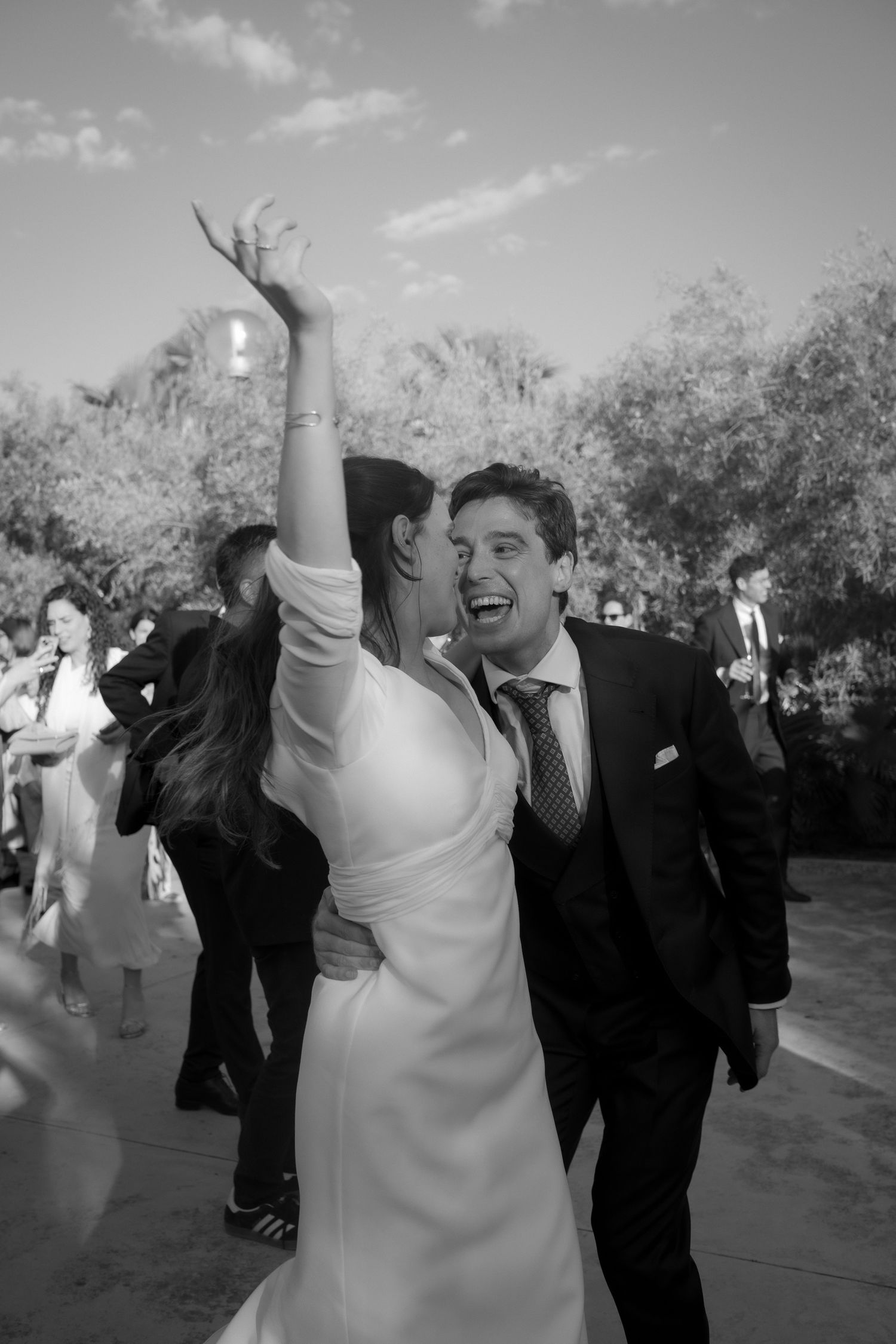 Wedding couple dances joyfully at their outdoor reception while guests celebrate.