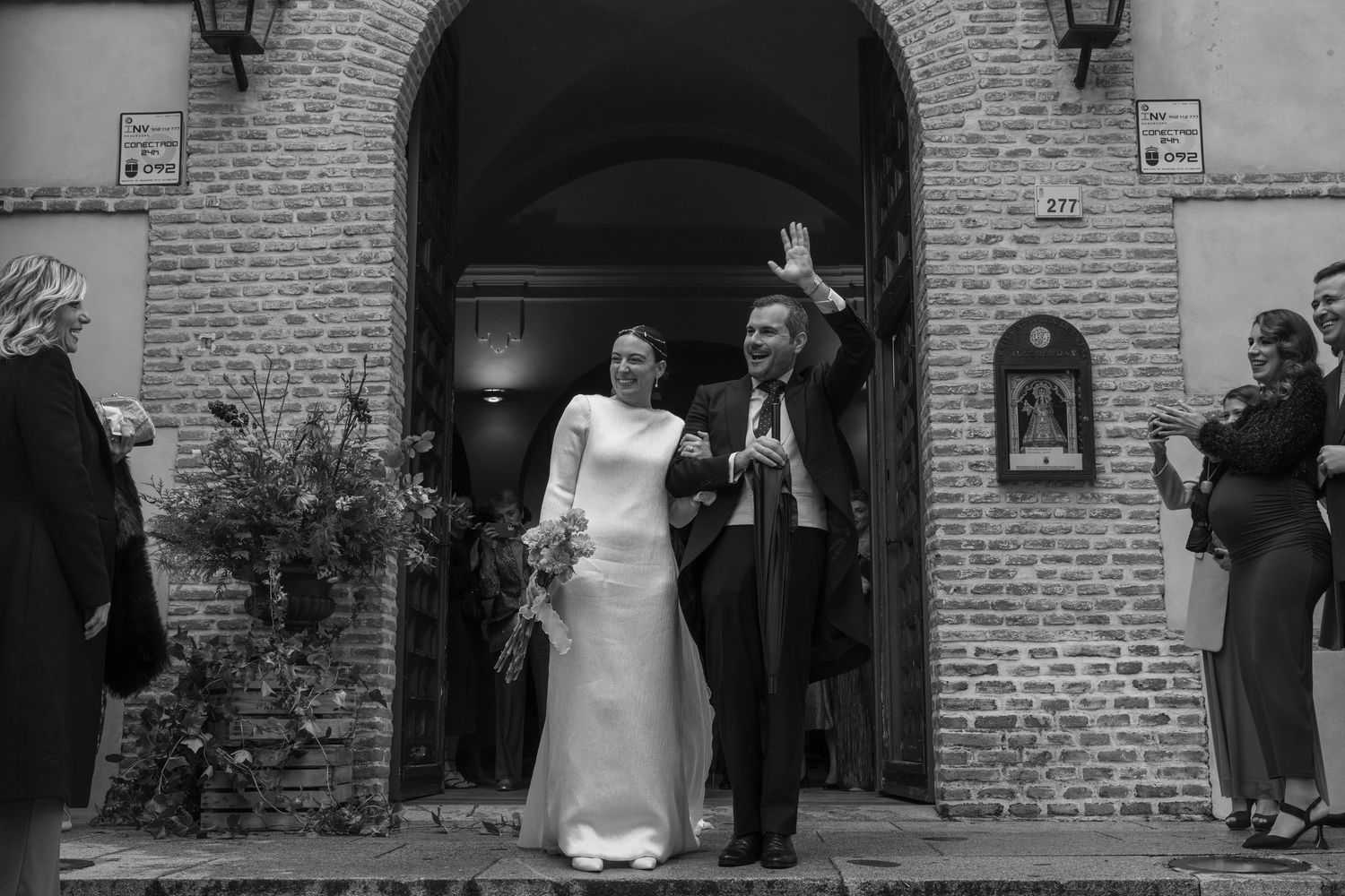 Bride and guests gathered outside brick church entrance during wedding celebration.
