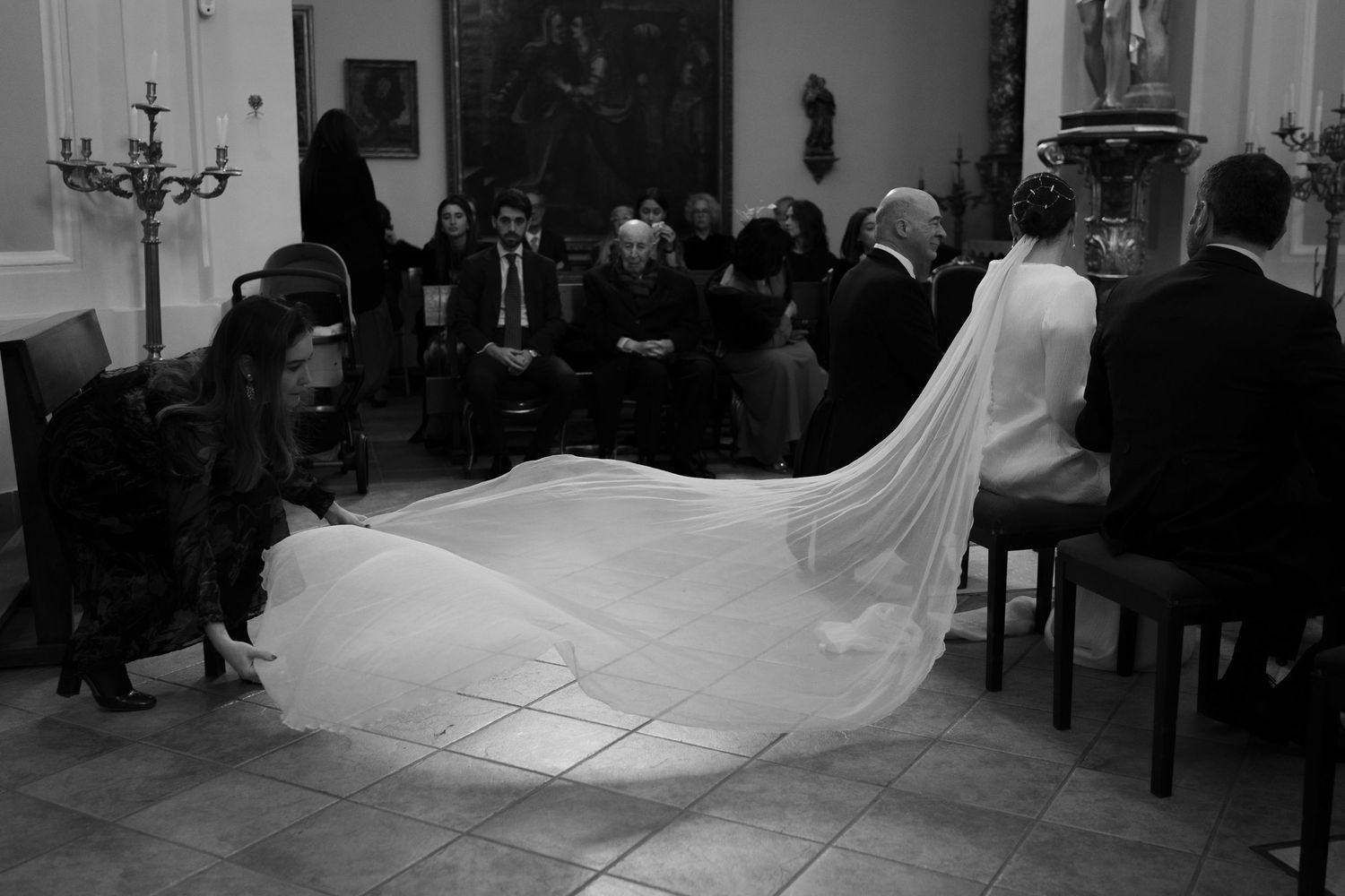 Wedding ceremony in progress inside traditional church with long bridal veil visible.