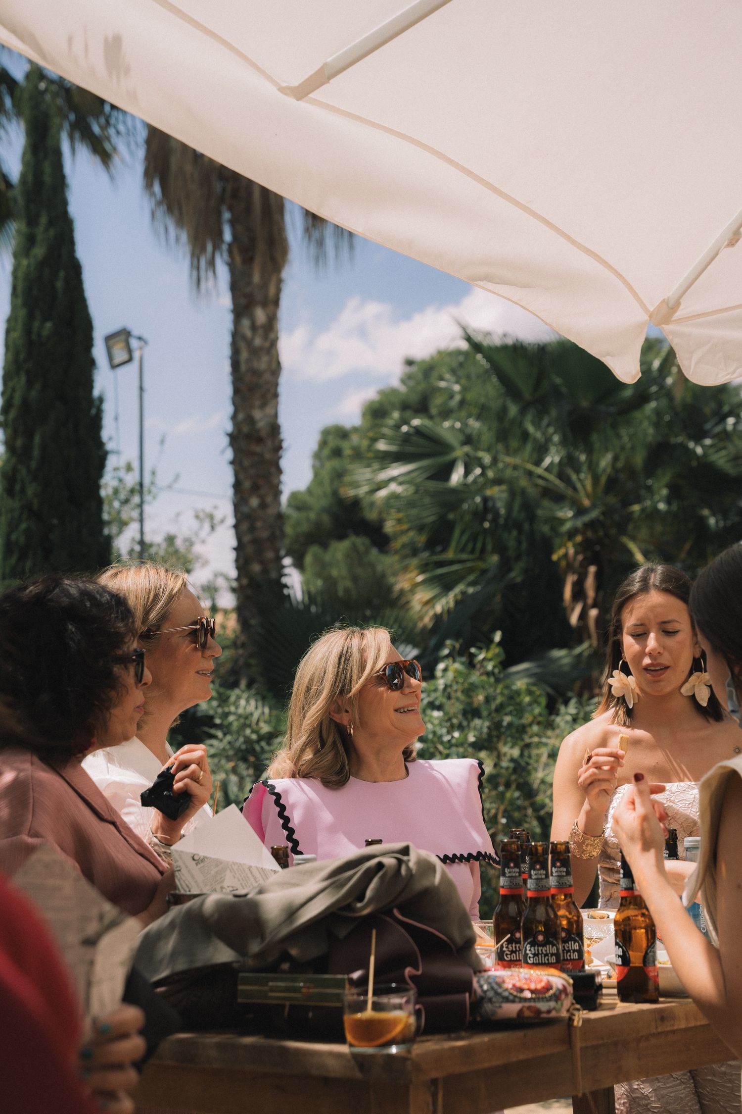 Wedding guests enjoying drinks and conversation at an outdoor reception under palm trees.