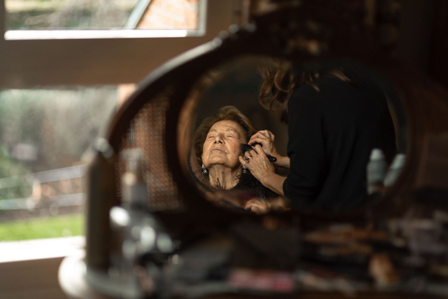 Reflection in mirror showing makeup application preparation.