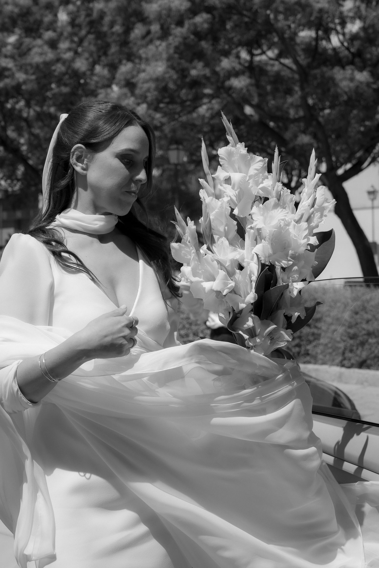 Woman in white dress twirling with flowers in an outdoor garden setting.