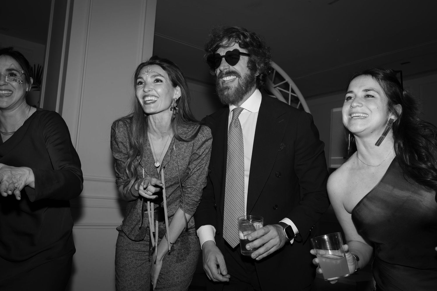 Group of people laughing and socializing at a black and white party photo.