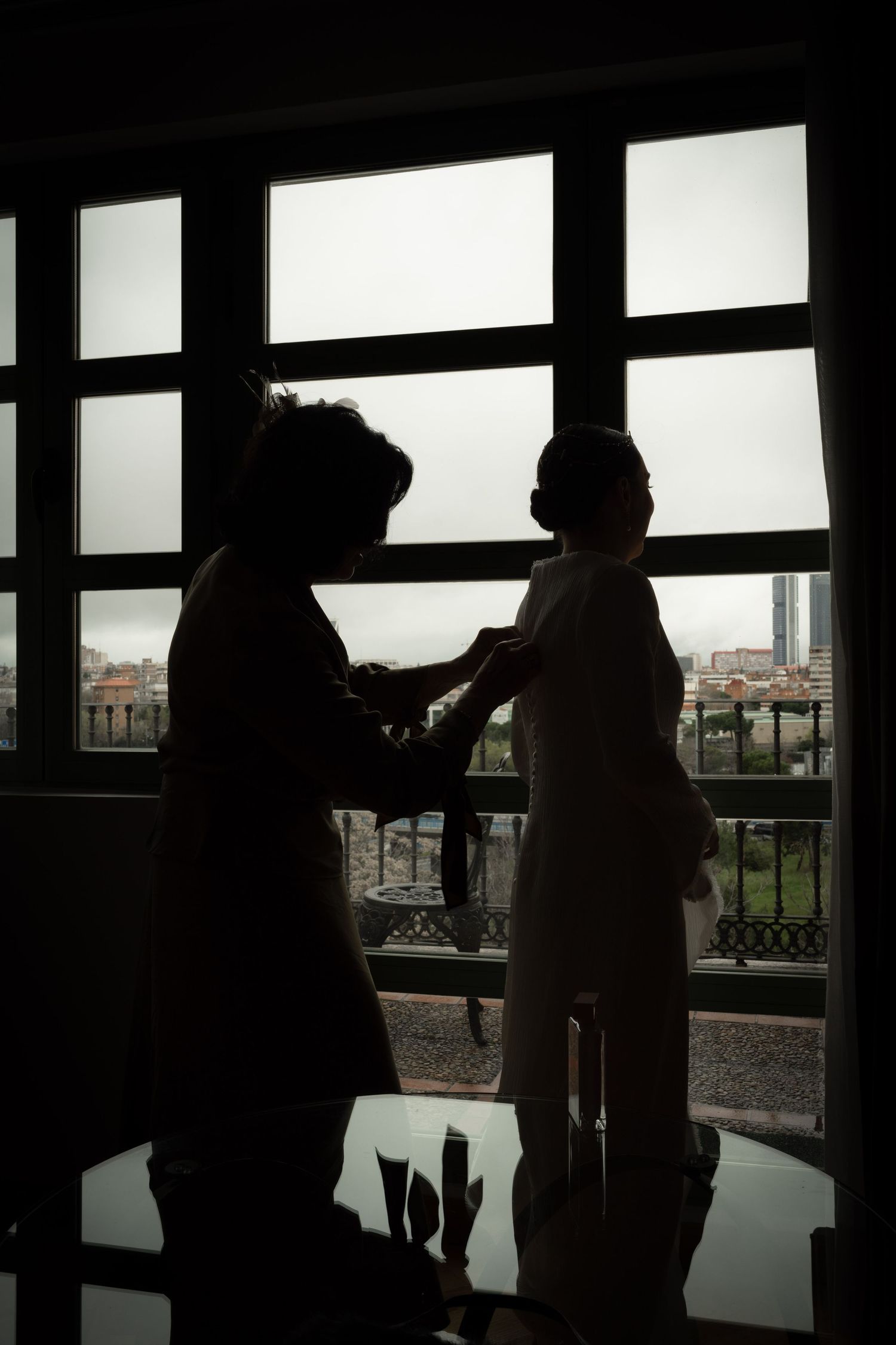 Silhouette of two figures by a window during a wedding preparation.