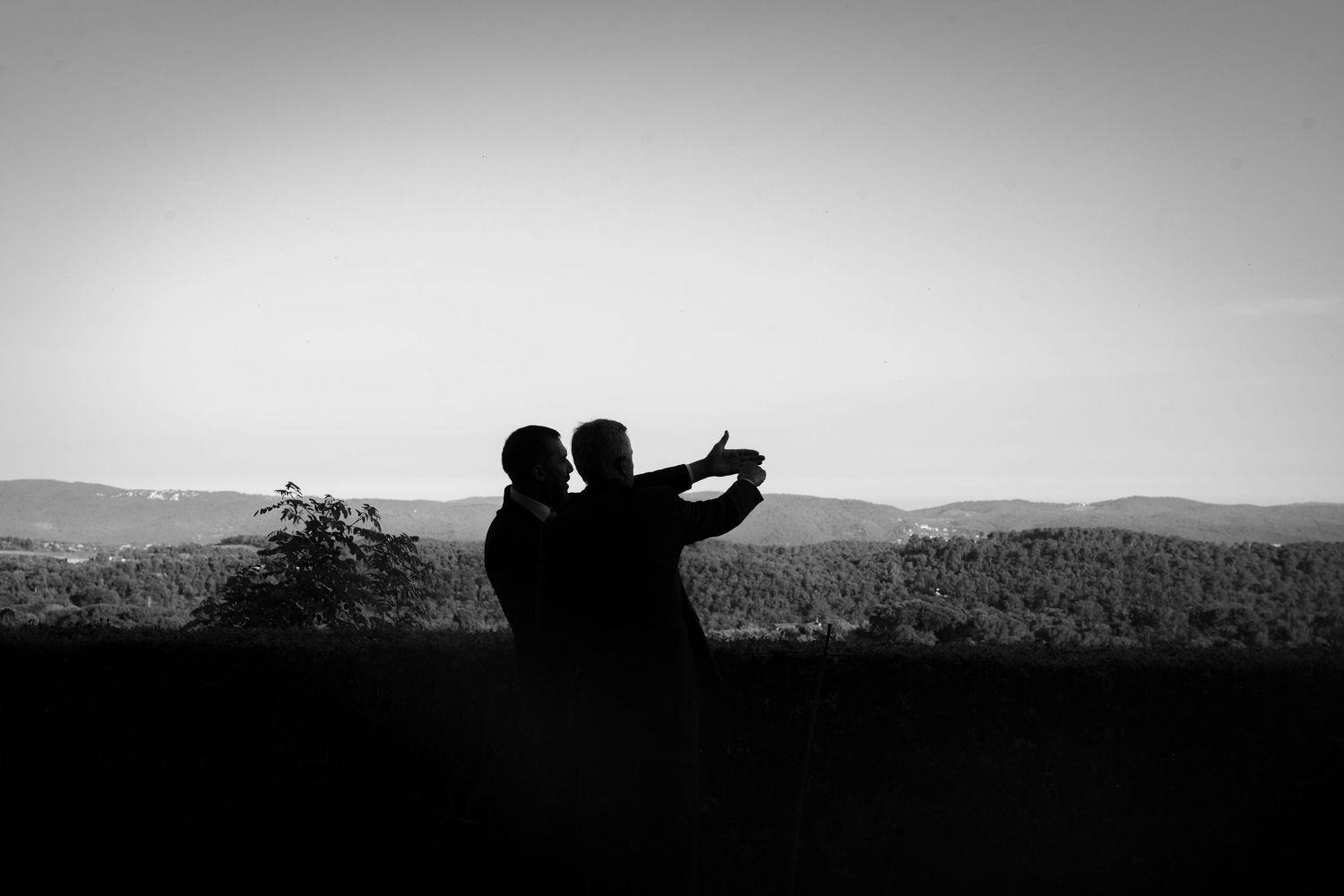 Black and white panoramic silhouettes against a mountain landscape at sunset.