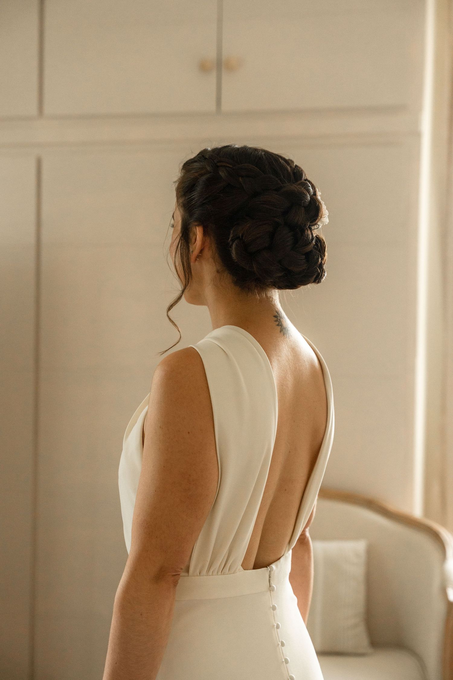 Back view of elegant updo hairstyle and white dress with open back detail.