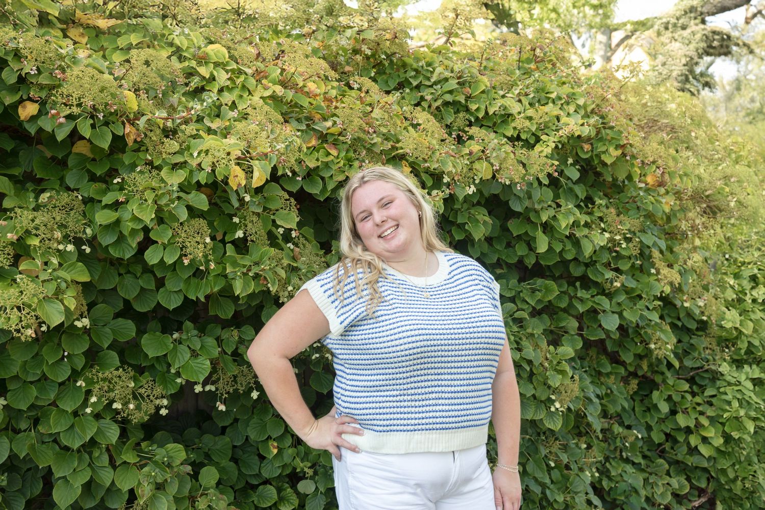 Summer portrait in striped shirt against lush green foliage background.