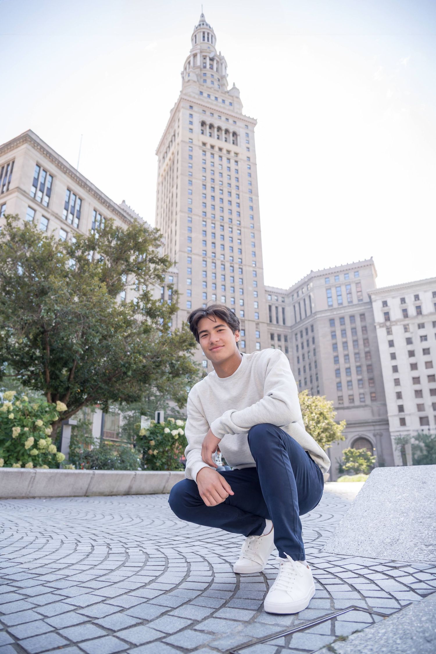Urban photoshoot with tall city buildings and patterned stone plaza.