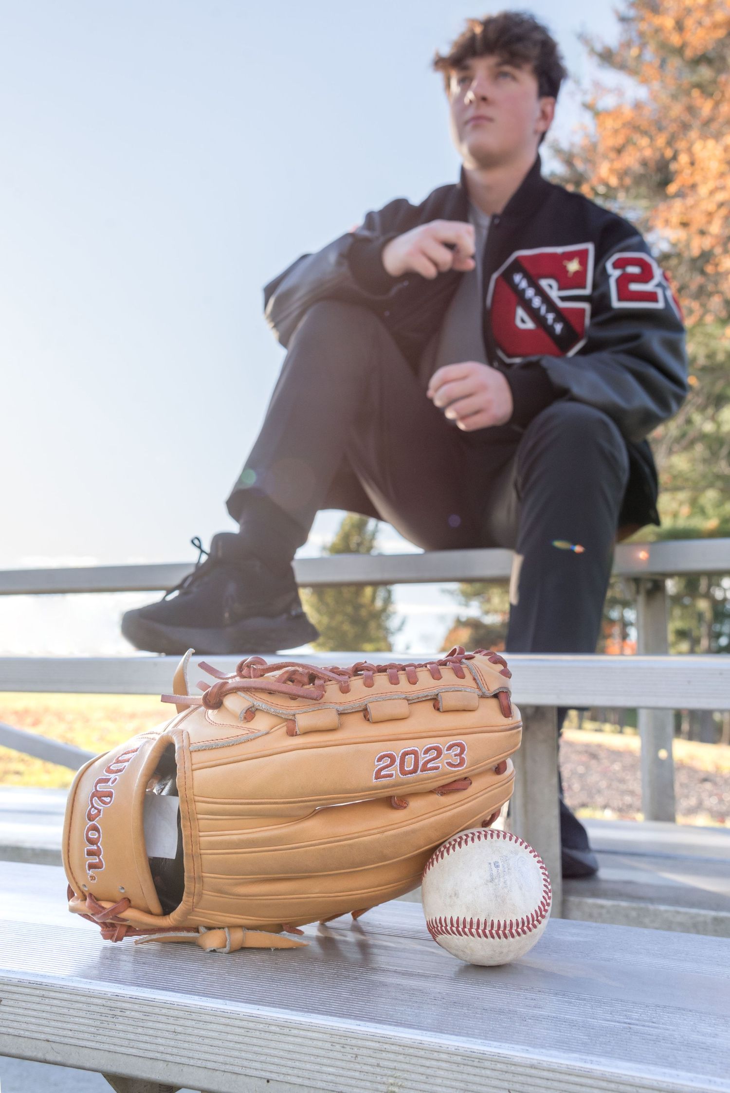 Wooden baseball bat and baseball displayed on wooden bench outdoors.