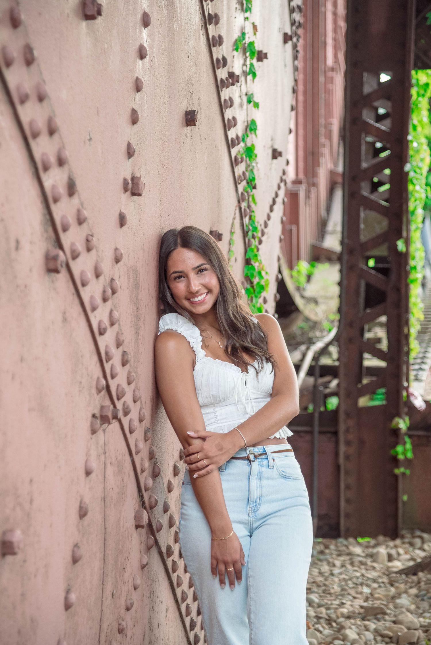 Portrait against an industrial metal wall with green vines and rivets creating texture.