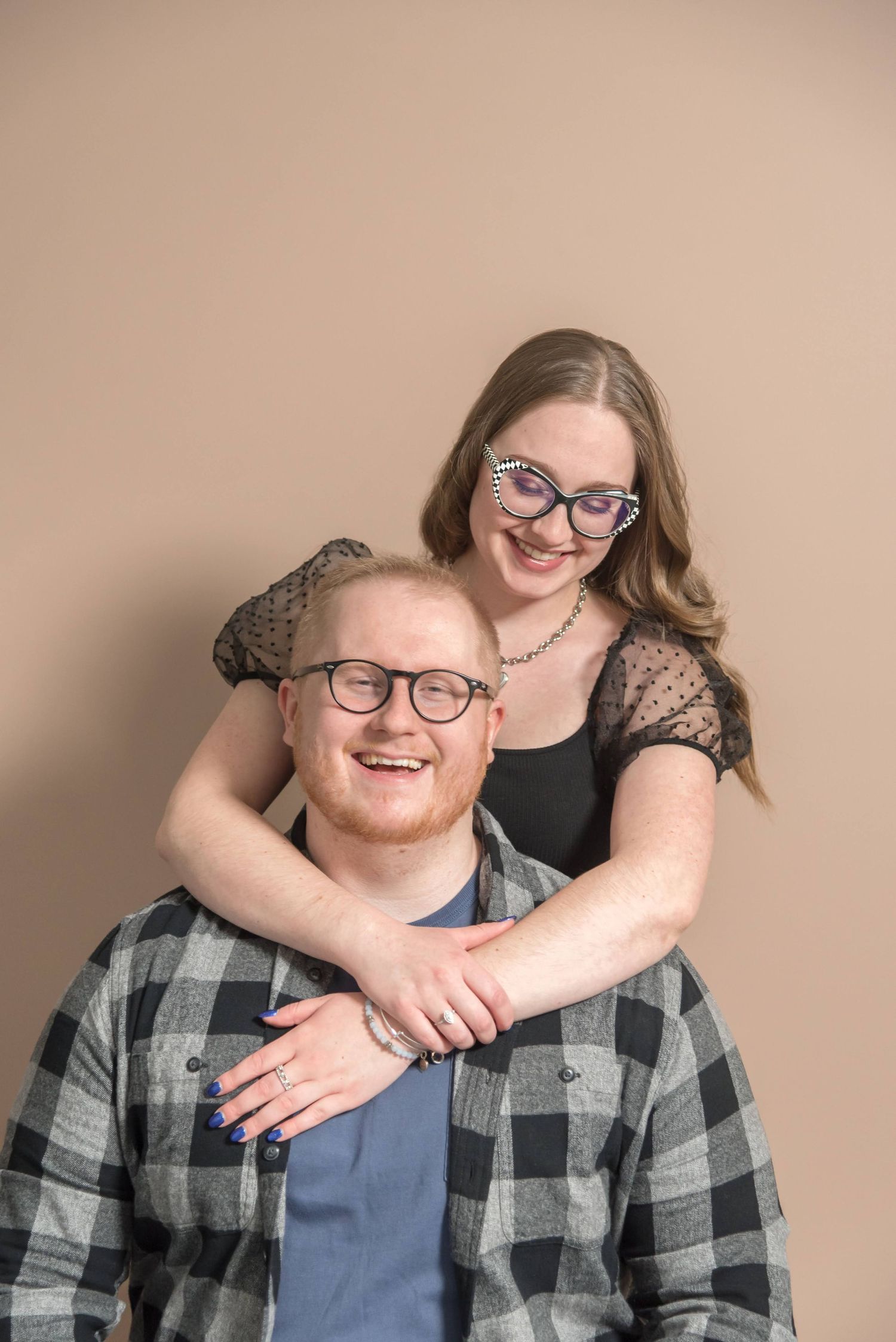 Couple sharing affectionate moments during casual portrait session against neutral background.
