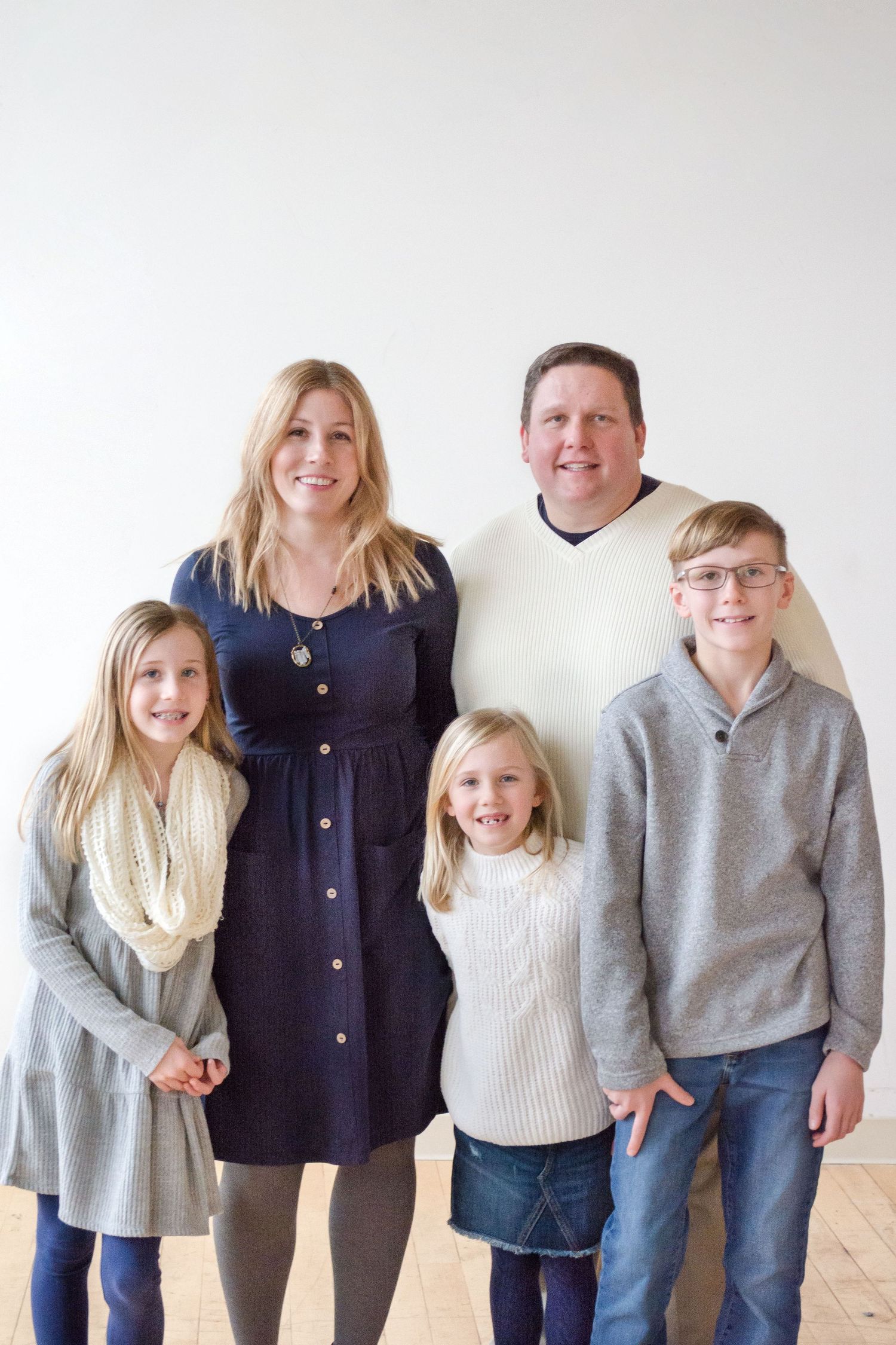 A studio portrait of a family of five against a white background.