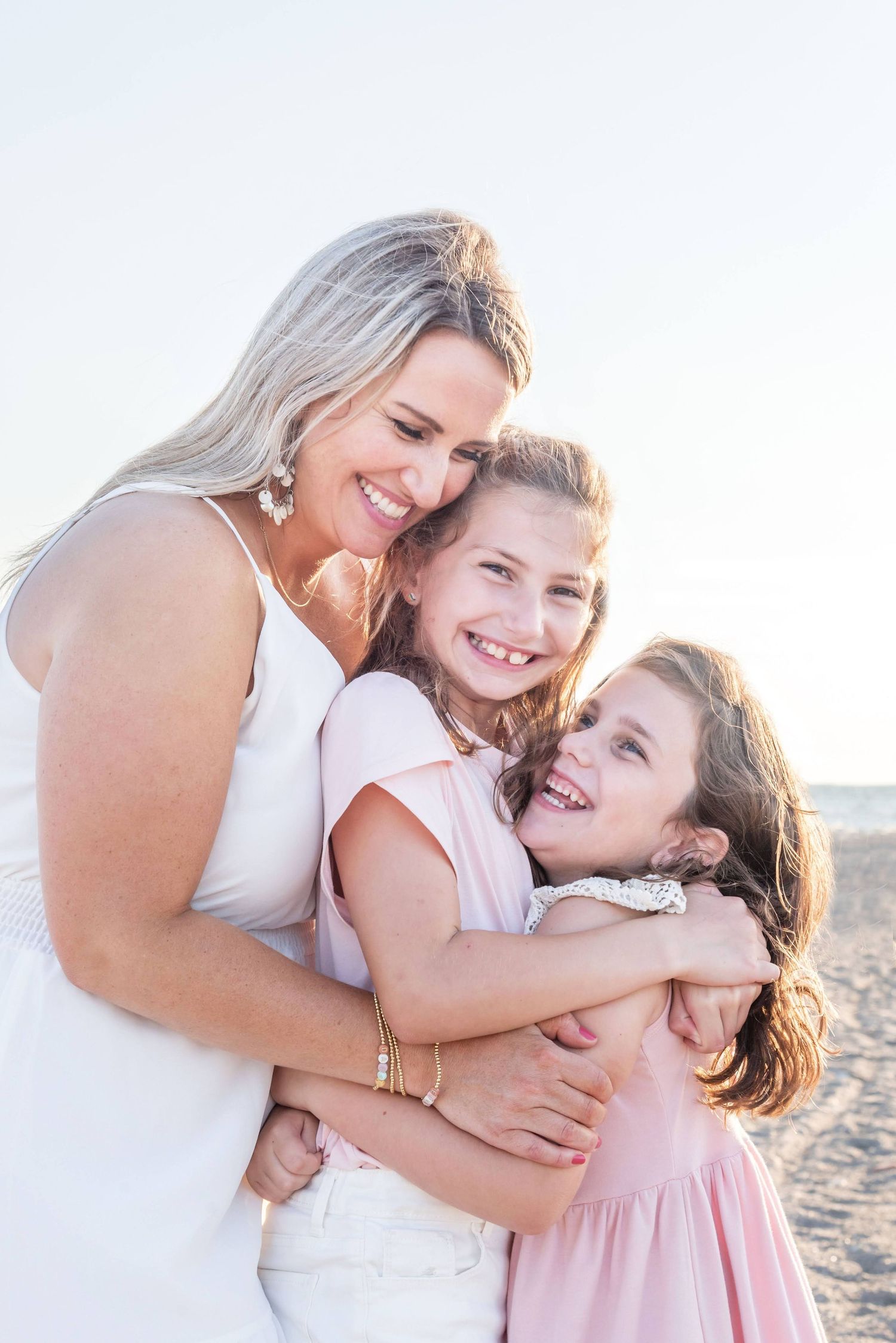 Candid beach portrait showing joyful embraces and laughter at sunset.