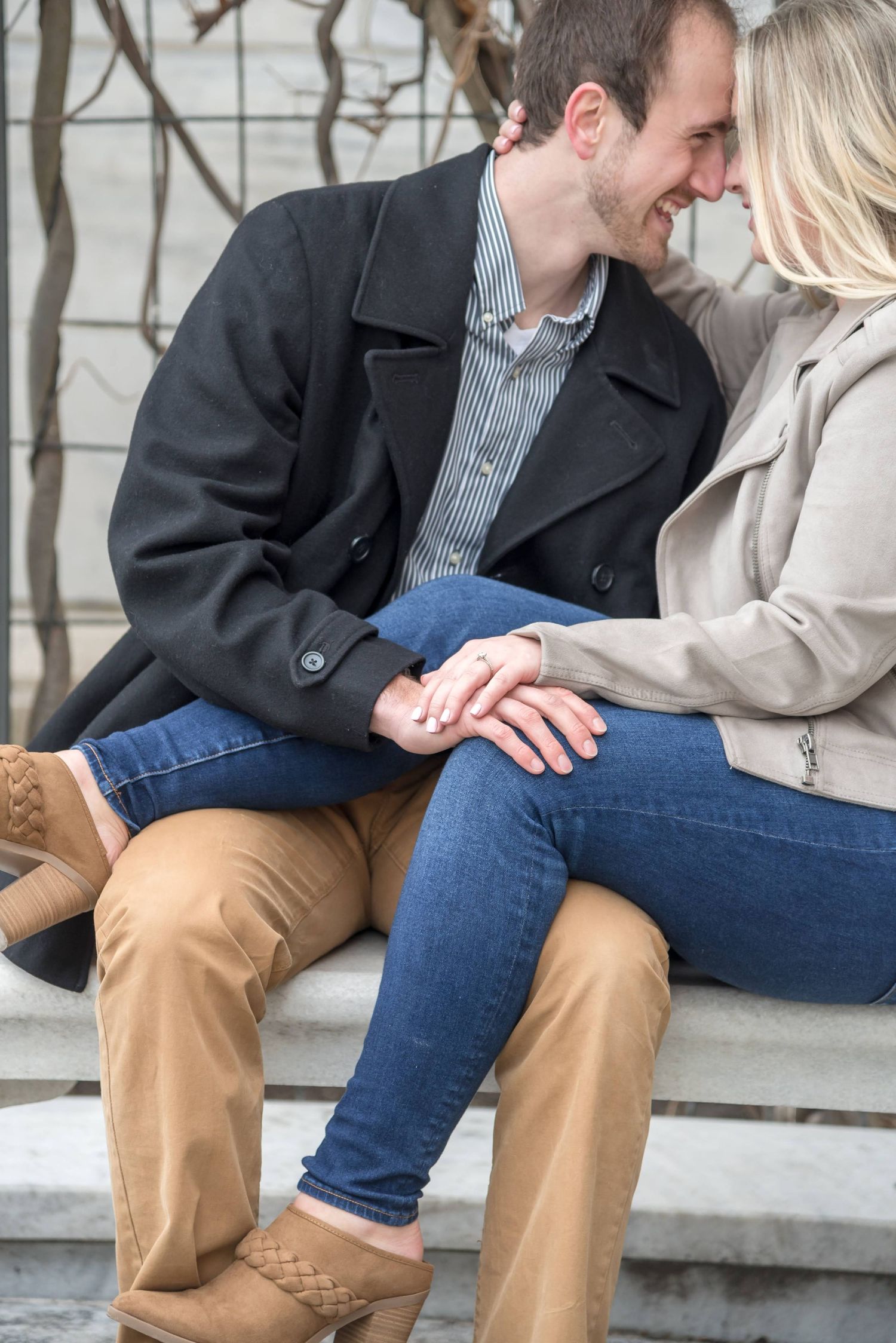 Couple sitting close together on concrete steps wearing casual clothing.