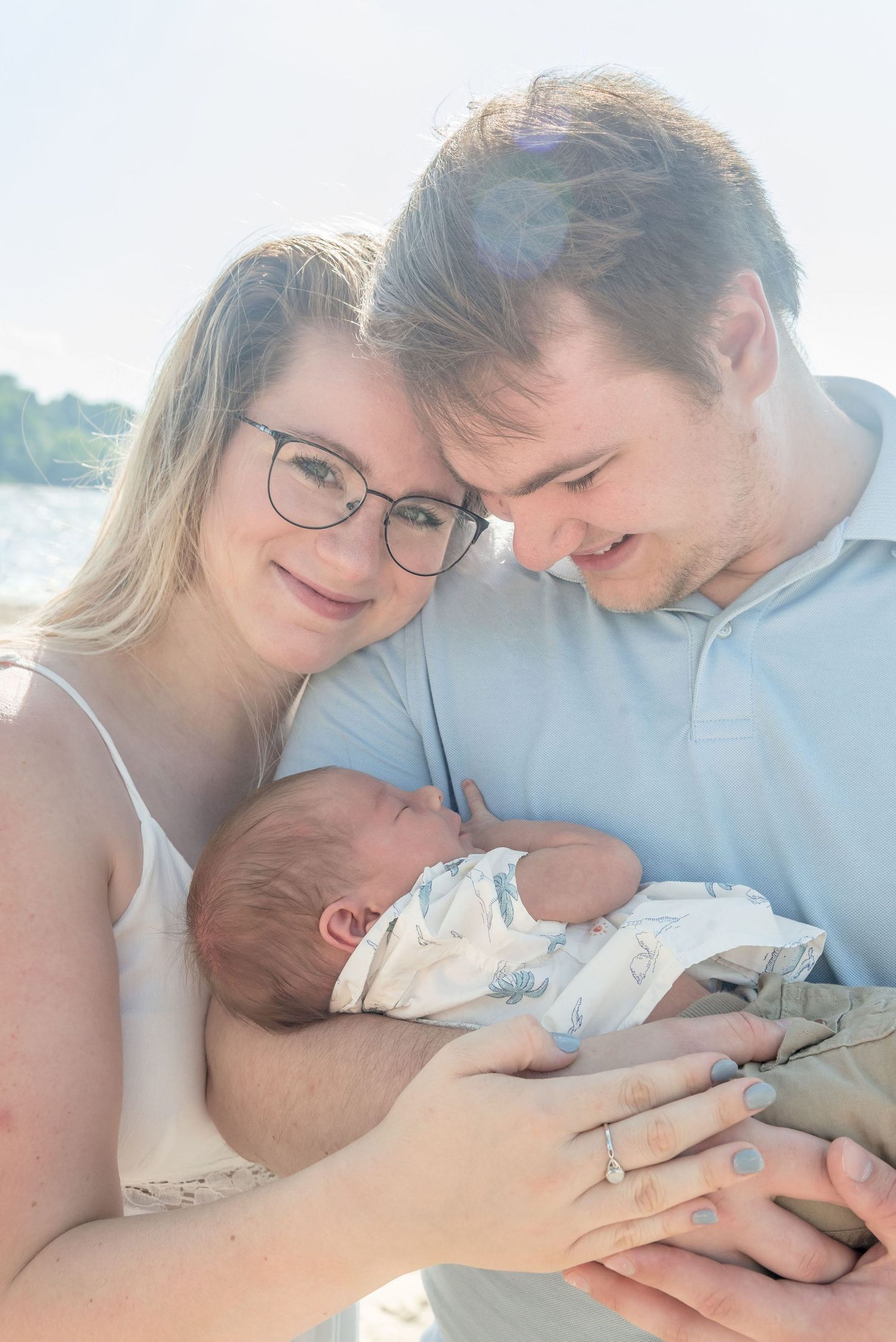 New parents sharing an intimate moment with their newborn baby outdoors.