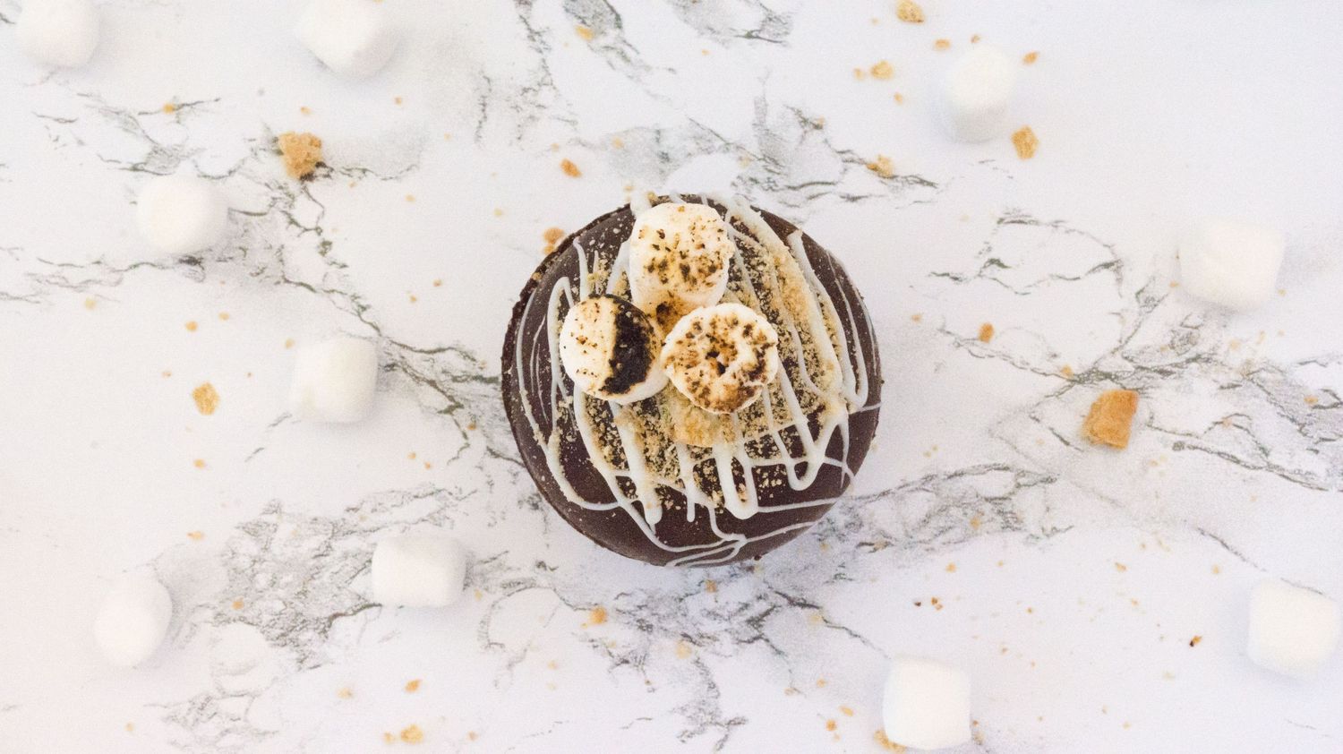 White marshmallows and sprinkles scattered on marble surface for food photography.