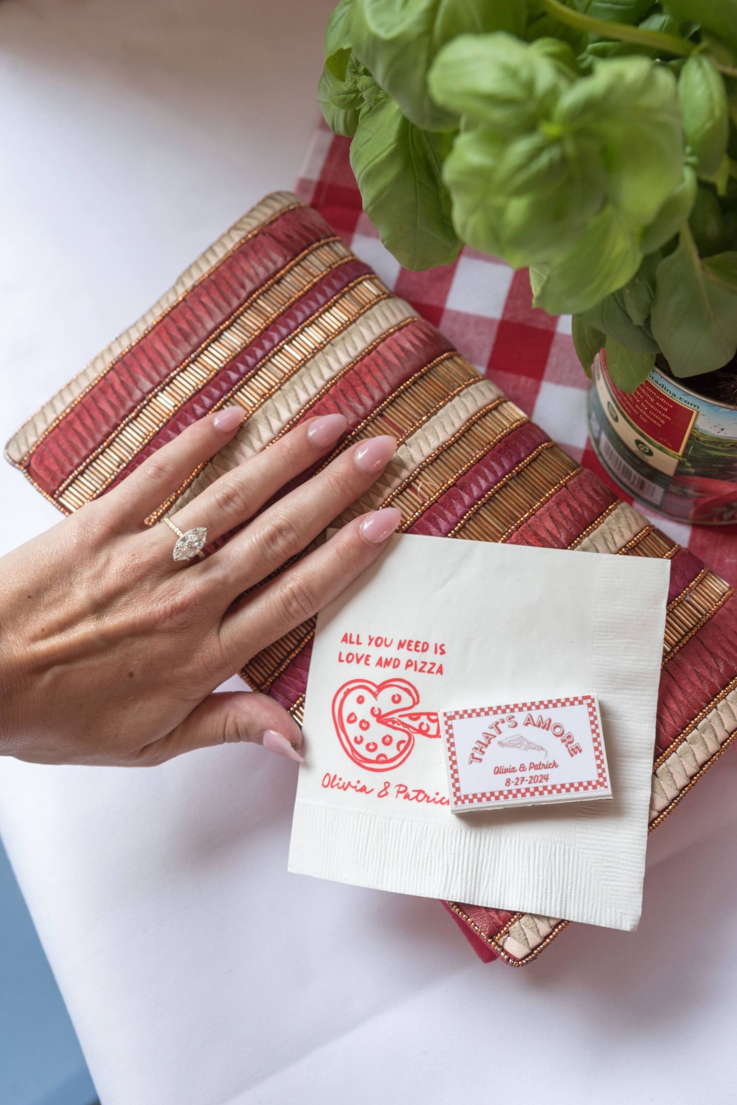Hand placing business cards with red text on a bamboo placemat next to fresh herbs.
