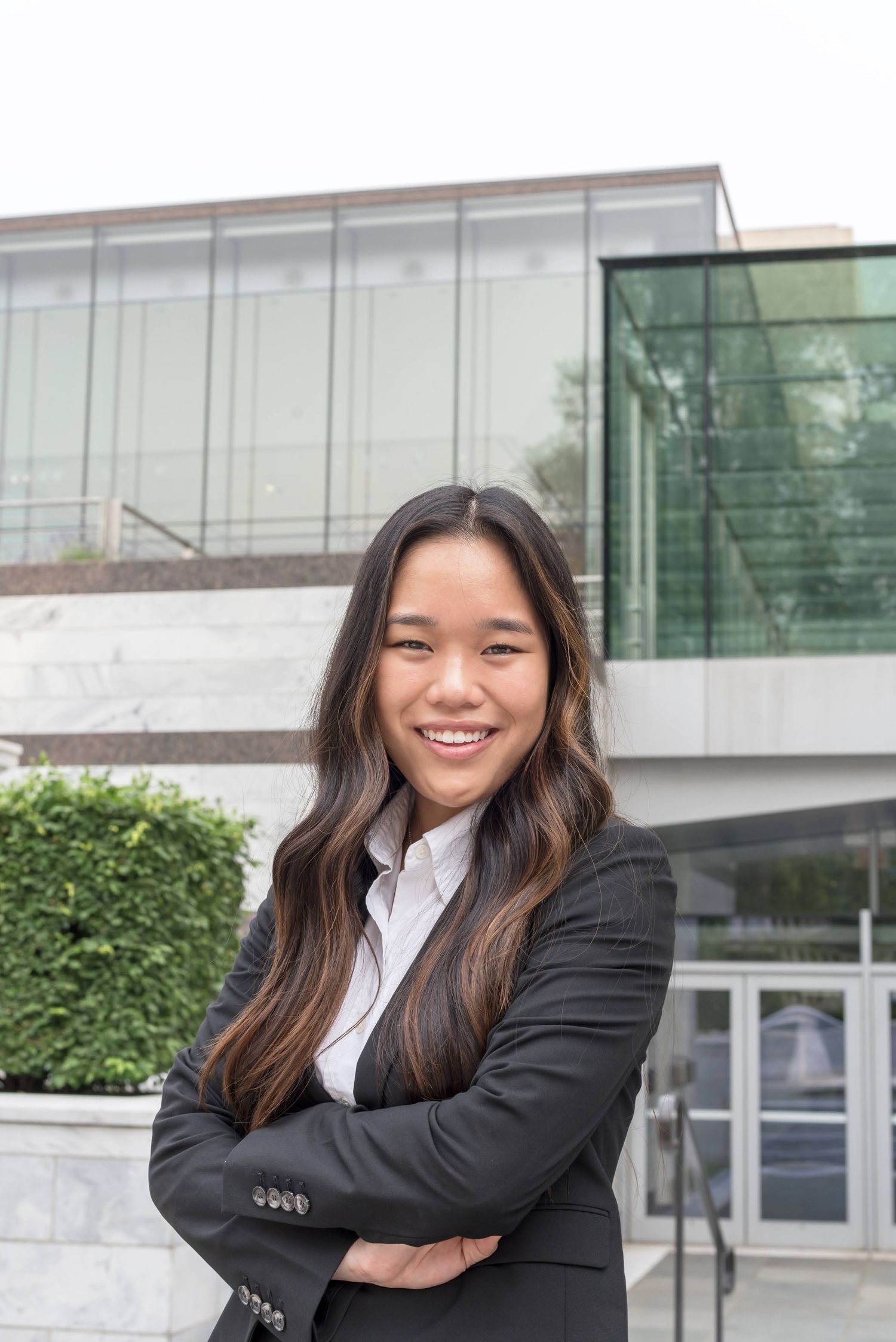 Professional headshots of woman in business attire against modern building exterior.