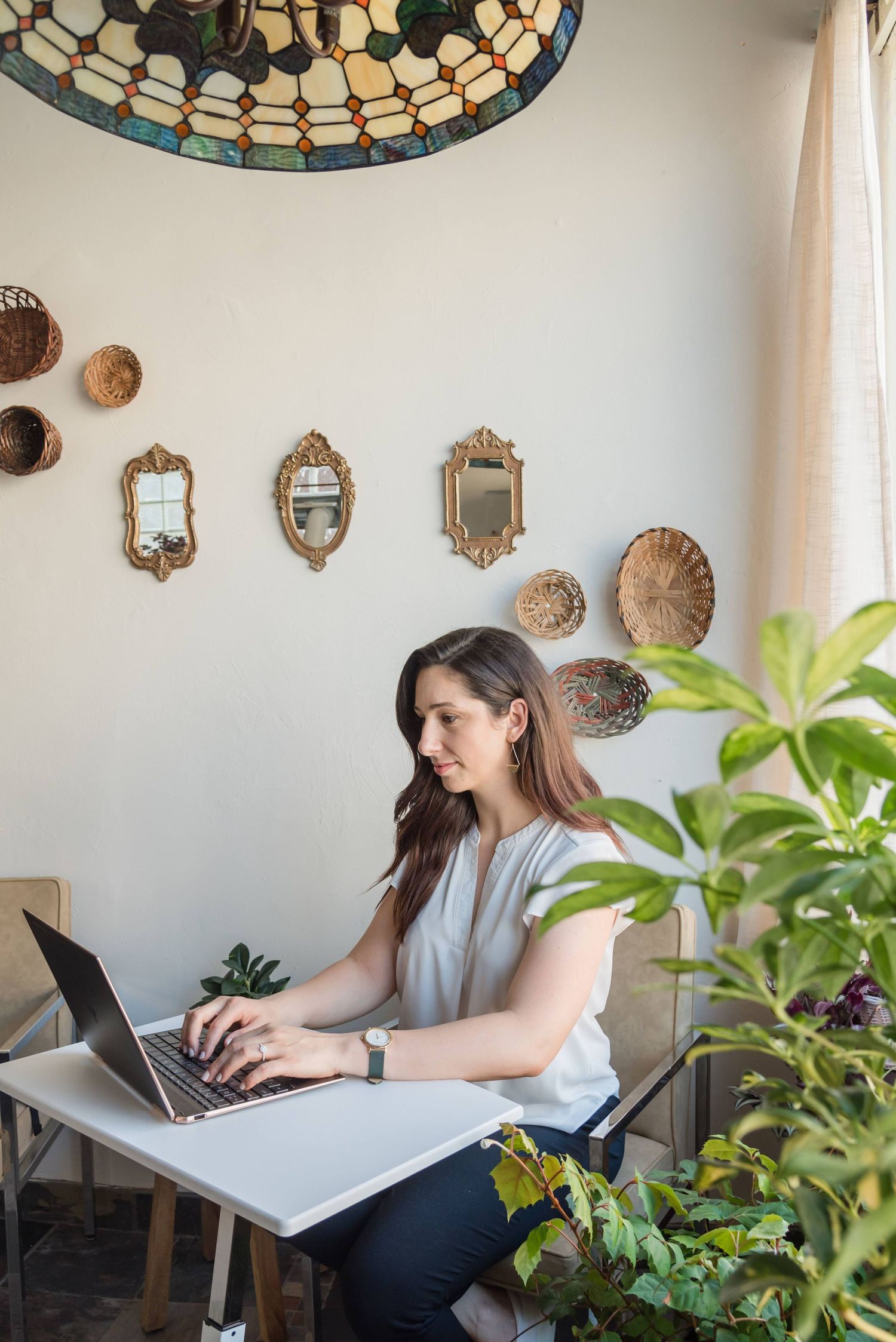 Modern home office workspace with decorative mirrors and plants.