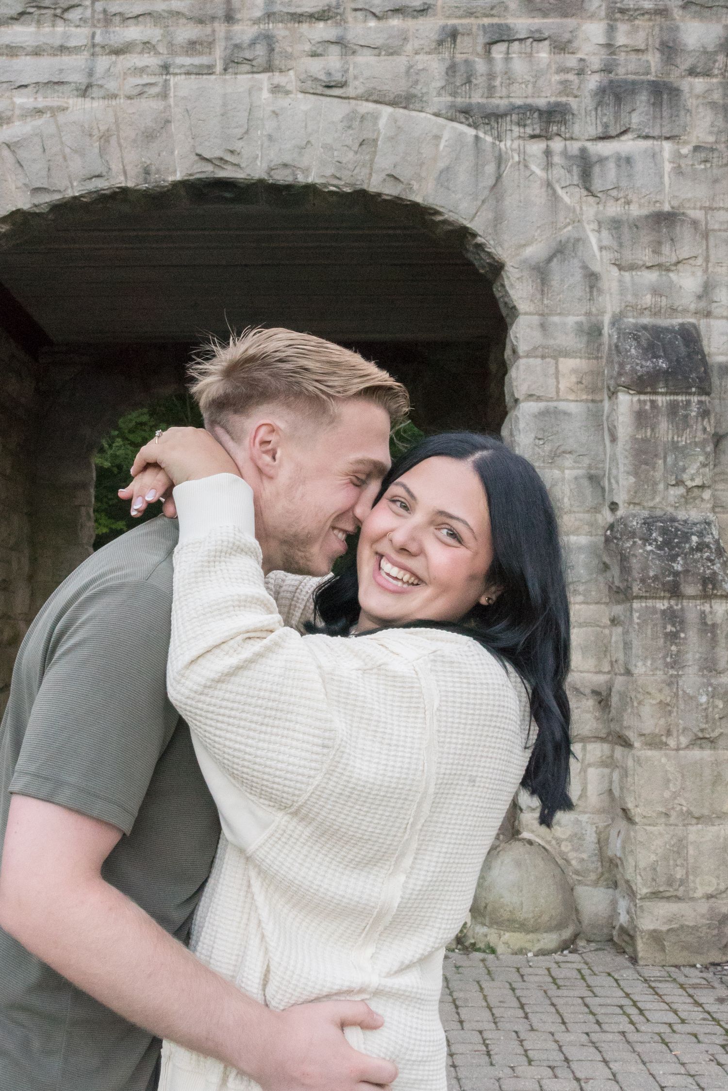 Couple sharing intimate moment against stone wall background.