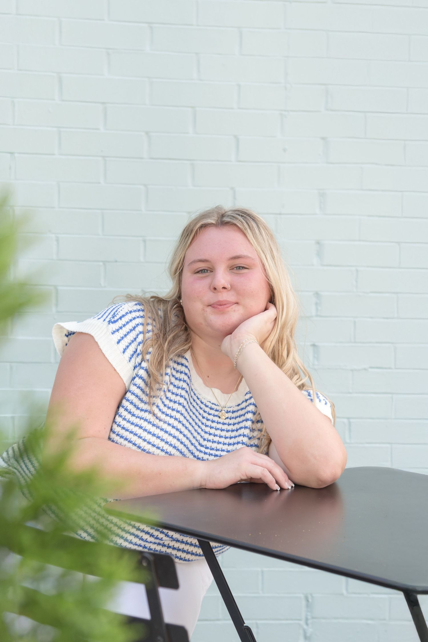 Casual portrait at white table against white brick wall with tropical plants.