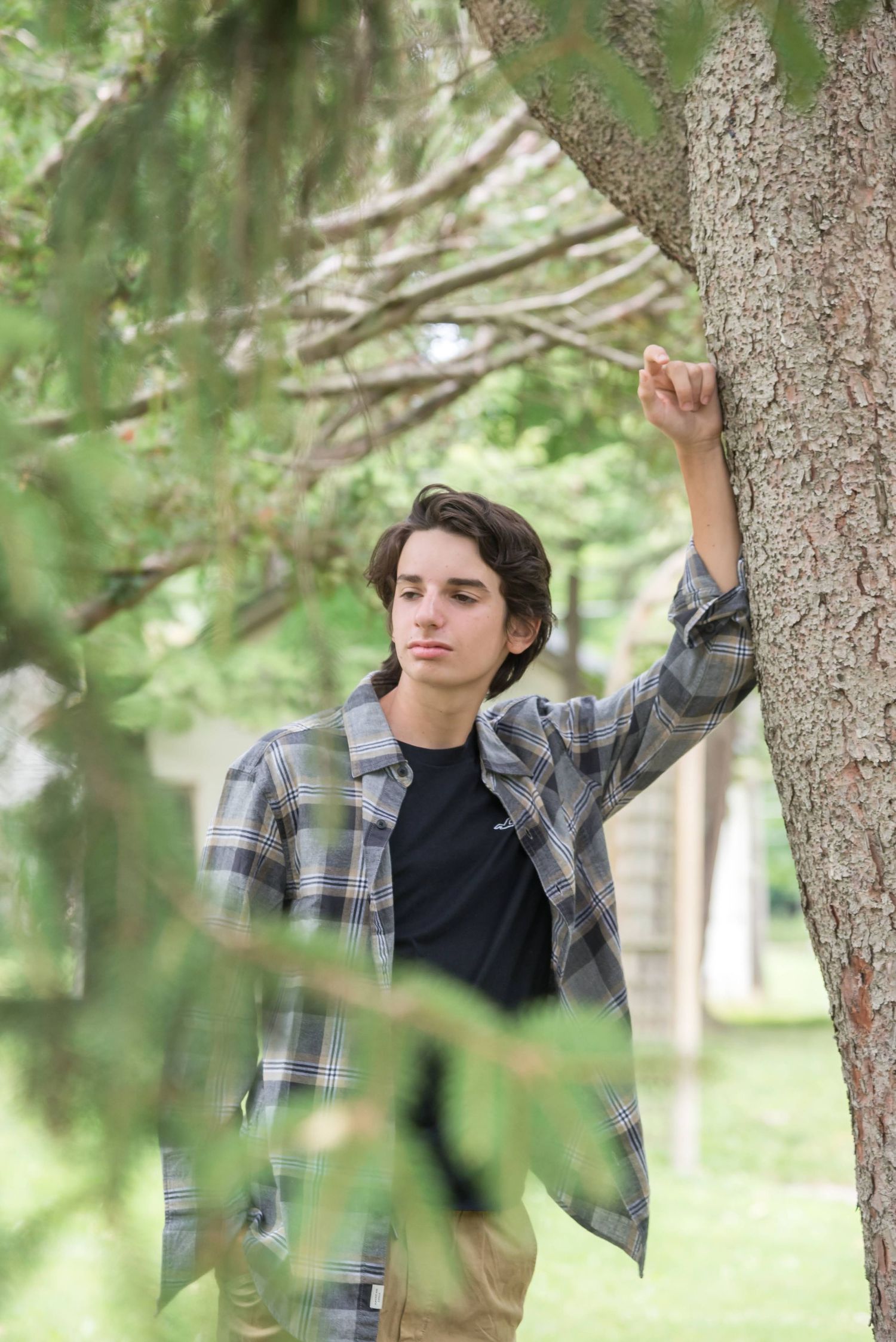 Artistic portraits among trees wearing plaid flannel in natural woodland setting.
