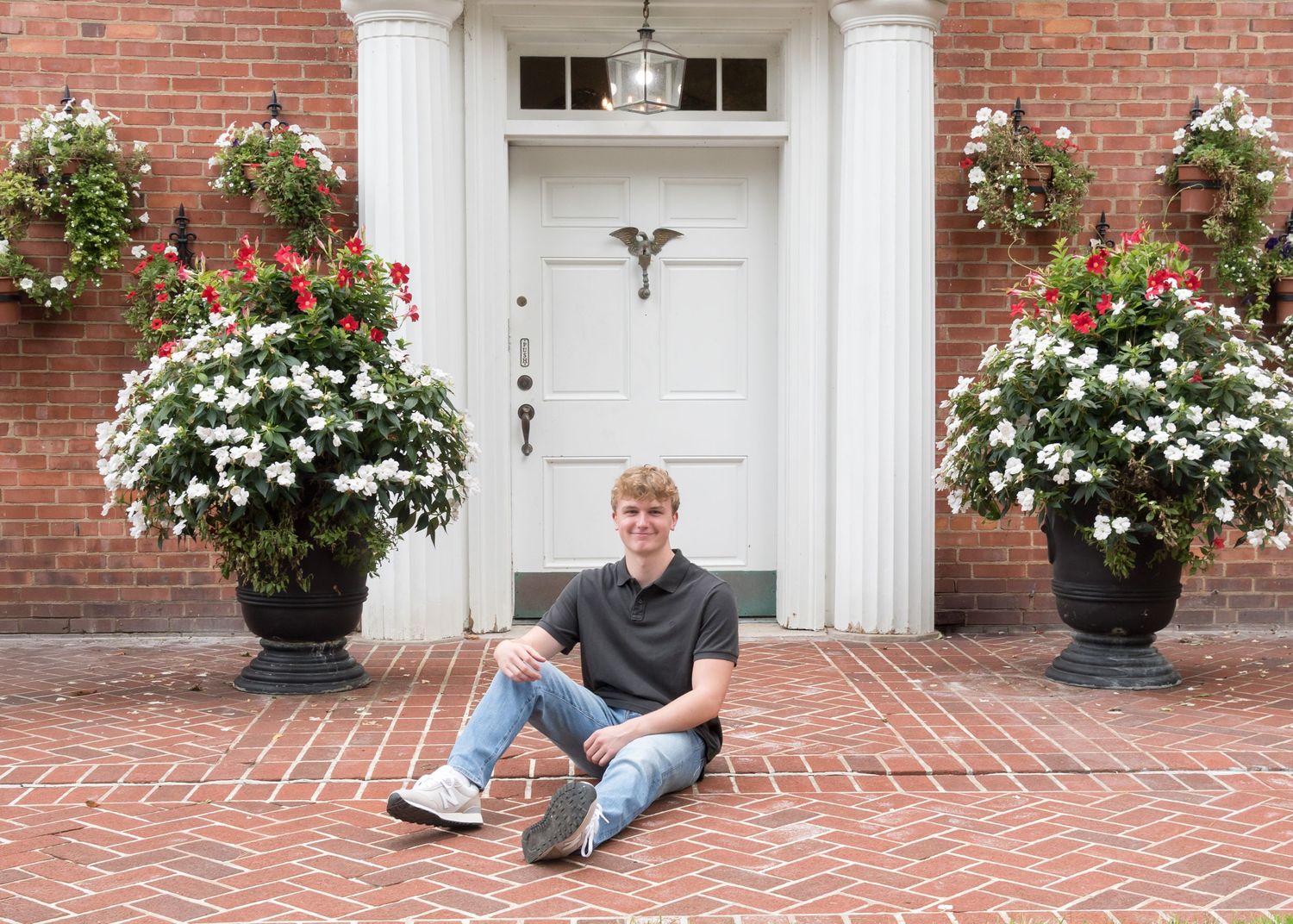 Red brick entrance with decorative flower pots and herringbone pattern walkway.