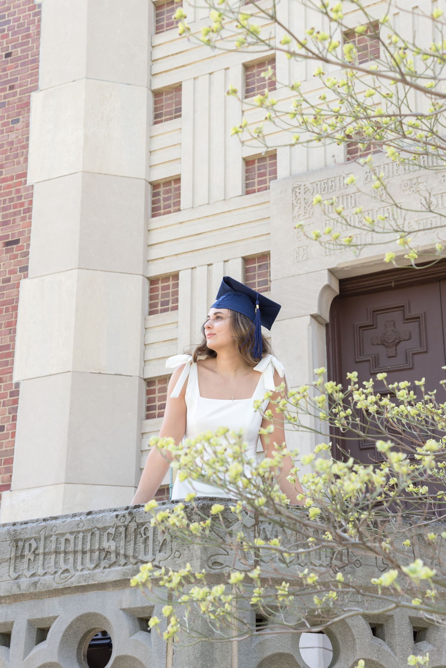 A graduation photo featuring spring blossoms and classical architecture in the background.