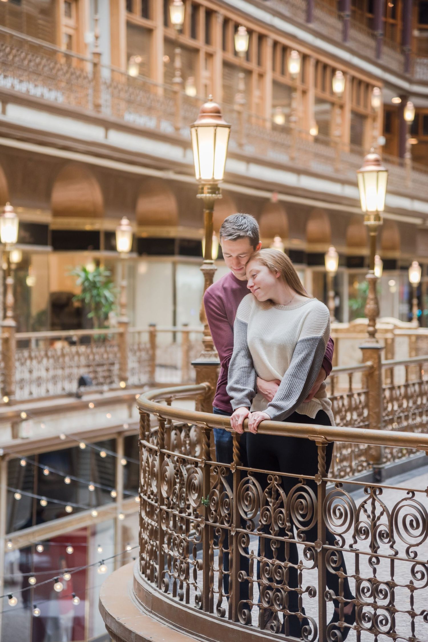 Romantic couple sharing intimate moment on ornate vintage balcony with glowing lanterns.