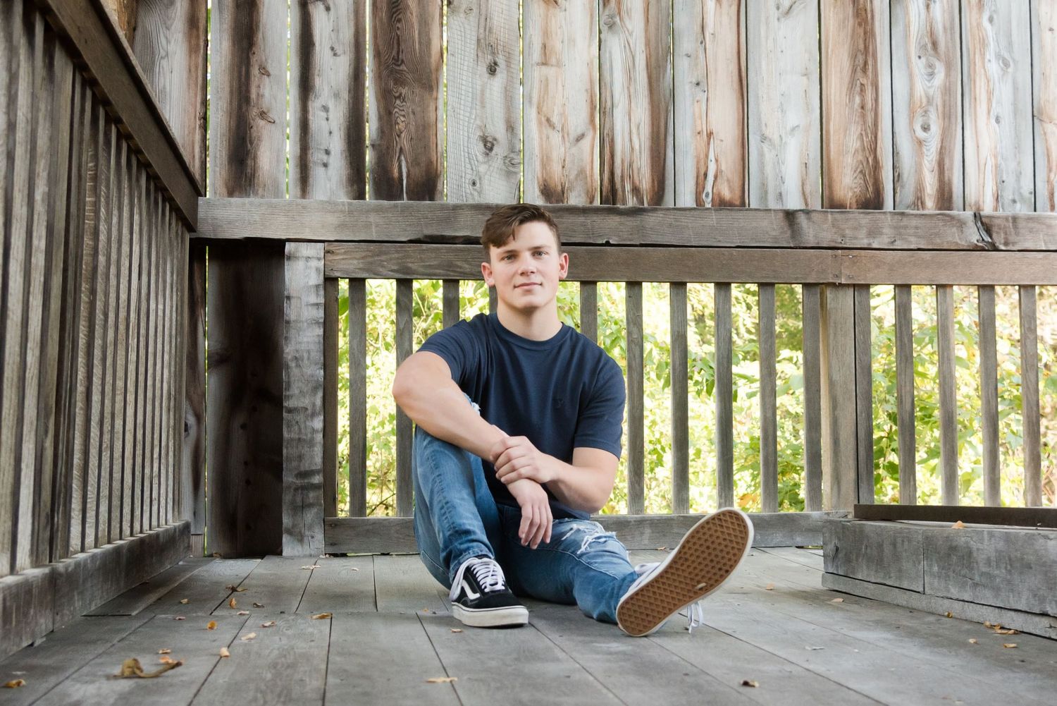 A casual portrait taken on a rustic wooden deck with natural lighting and architectural details.