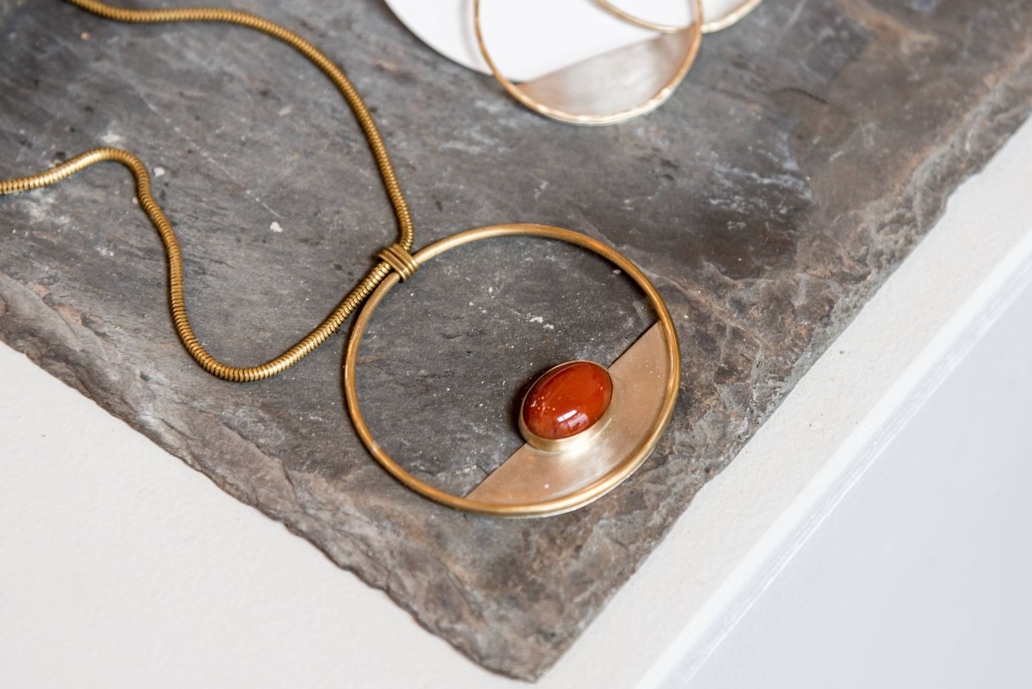 Close-up shots of copper wire jewelry details on dark stone surface.
