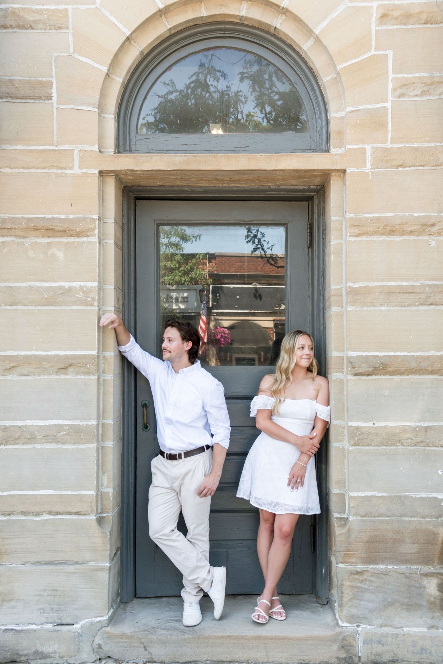 Creative poses against stone building with arched doorways and windows.