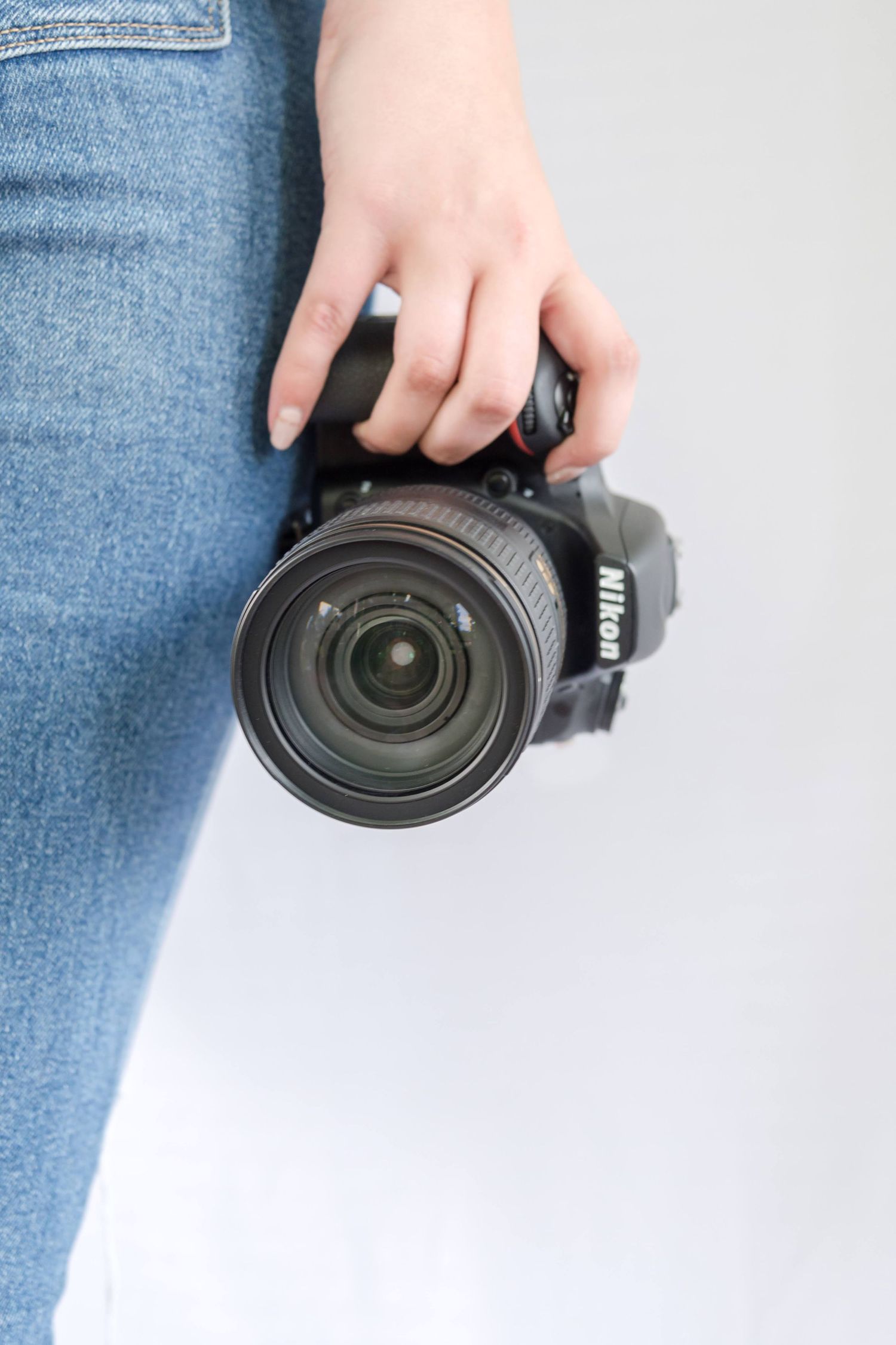 Close-up of camera lens being held against neutral background.