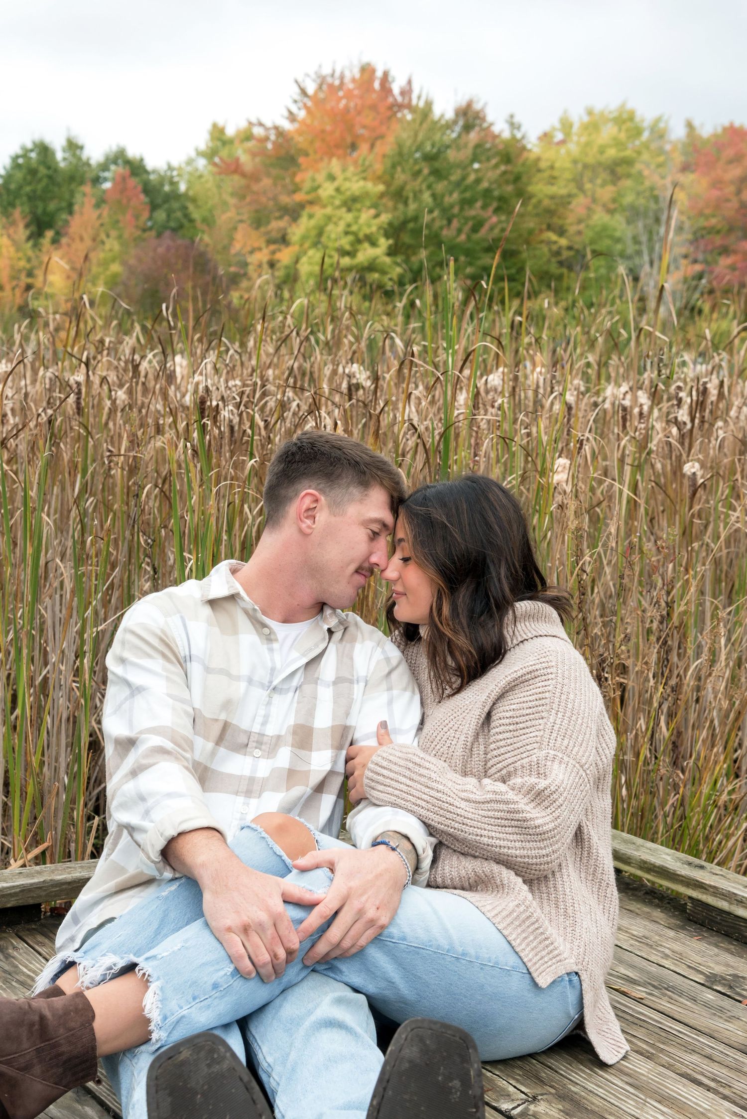 Romantic couple sharing intimate moments on wooden deck surrounded by autumn foliage.