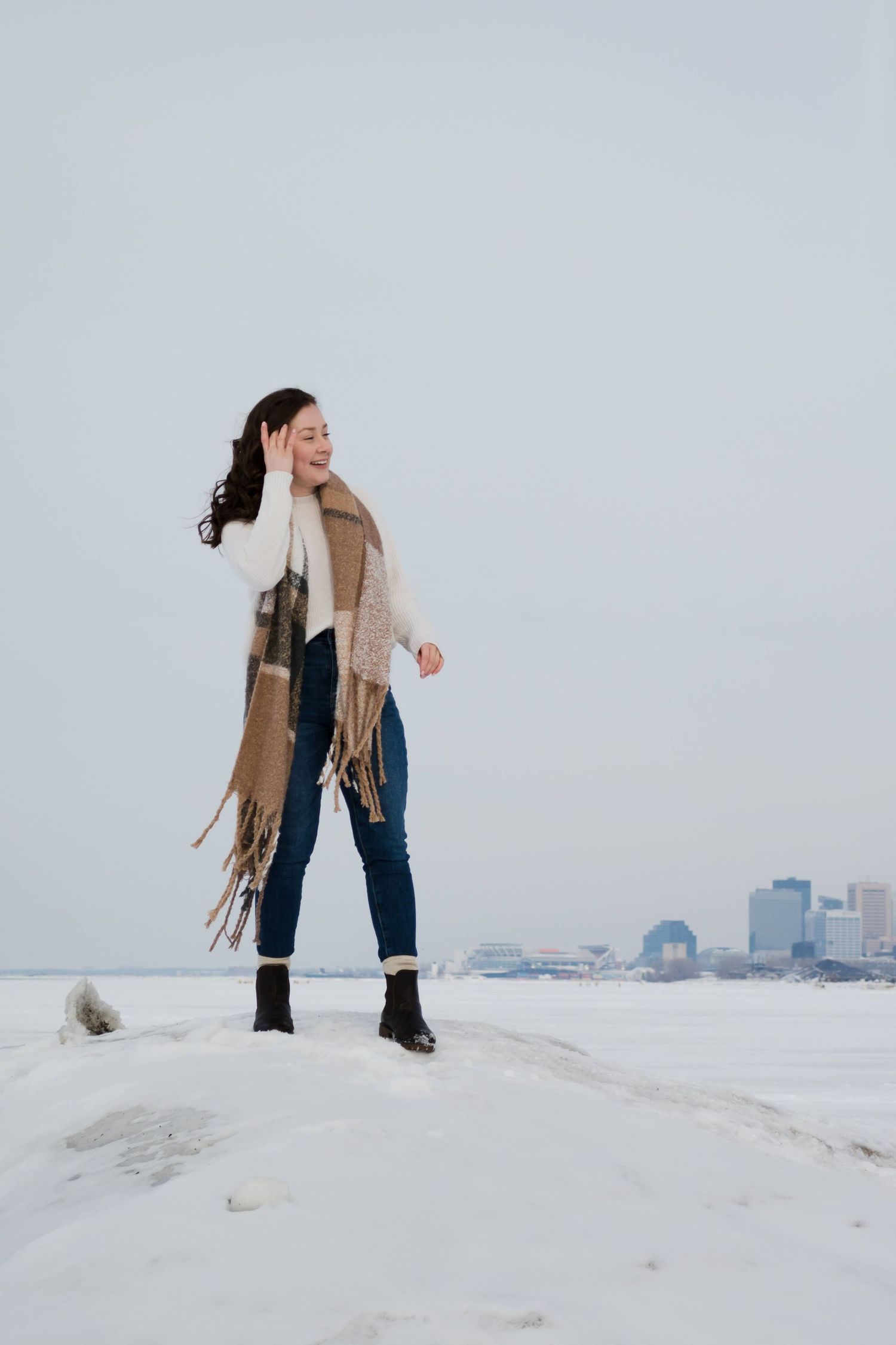 Winter scenes showing someone exploring snowy terrain with city skyline in background.