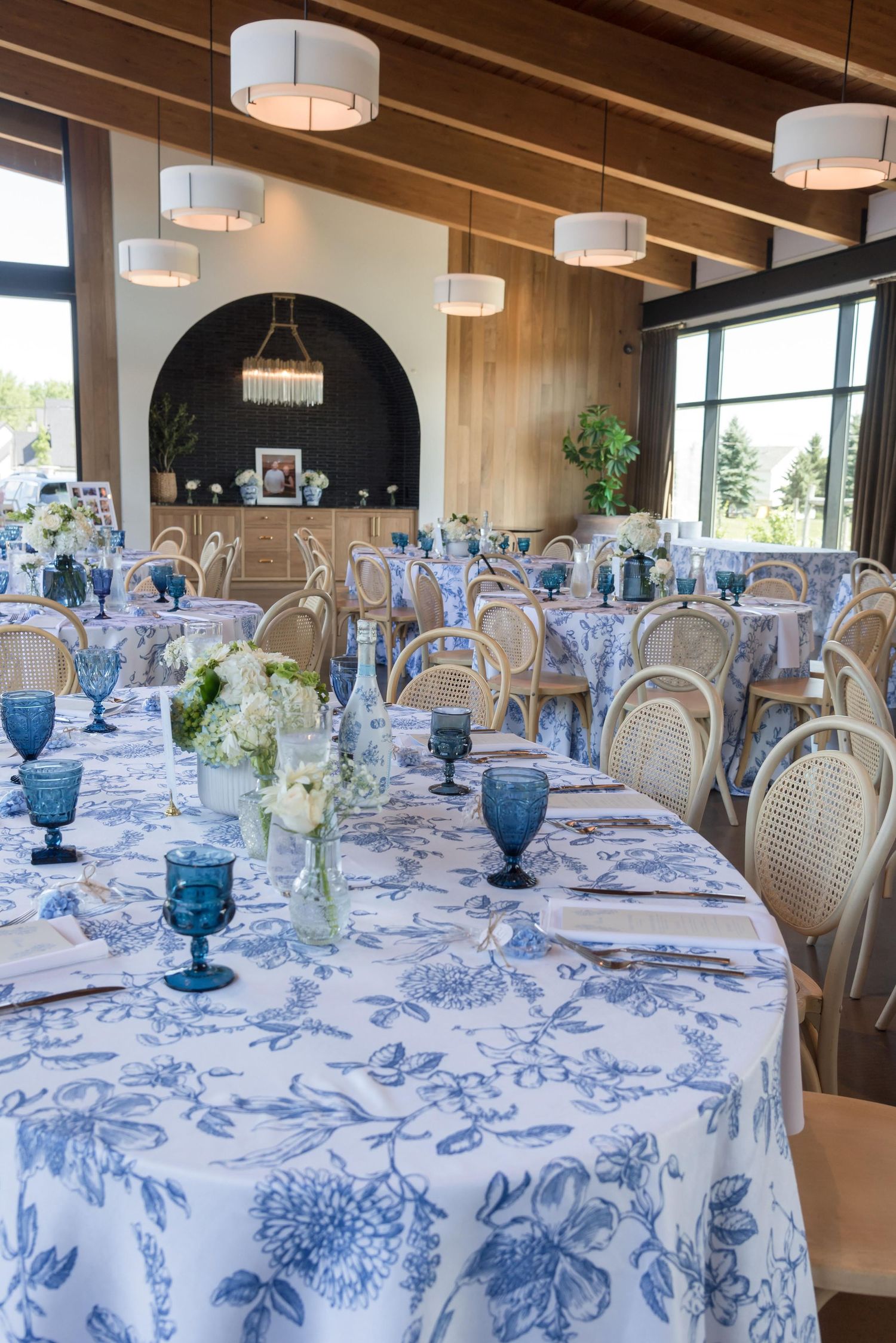 Elegant banquet hall setup with blue floral tablecloths and vintage glassware.