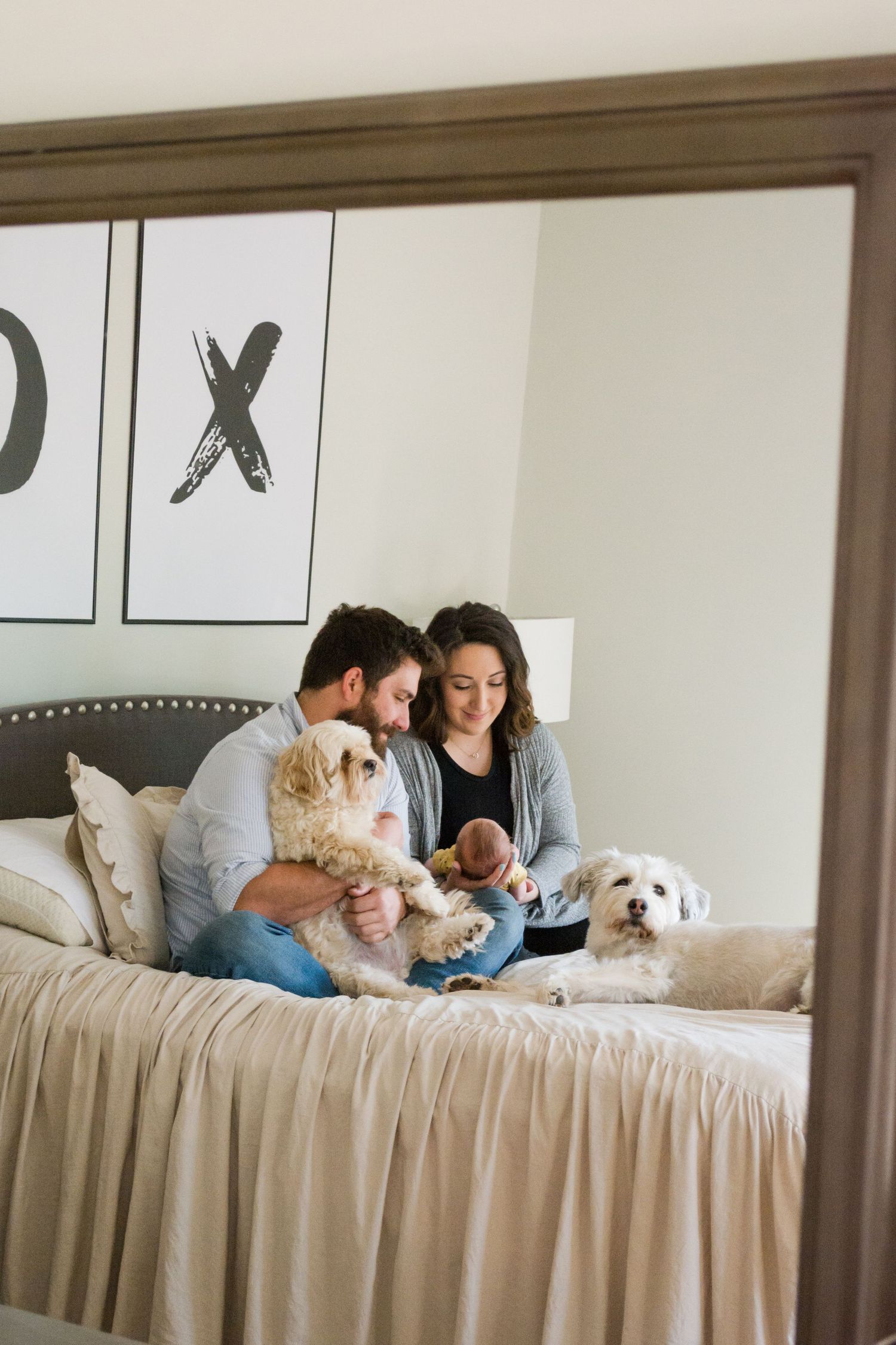 Family relaxing on bed with dog in bright modern bedroom.