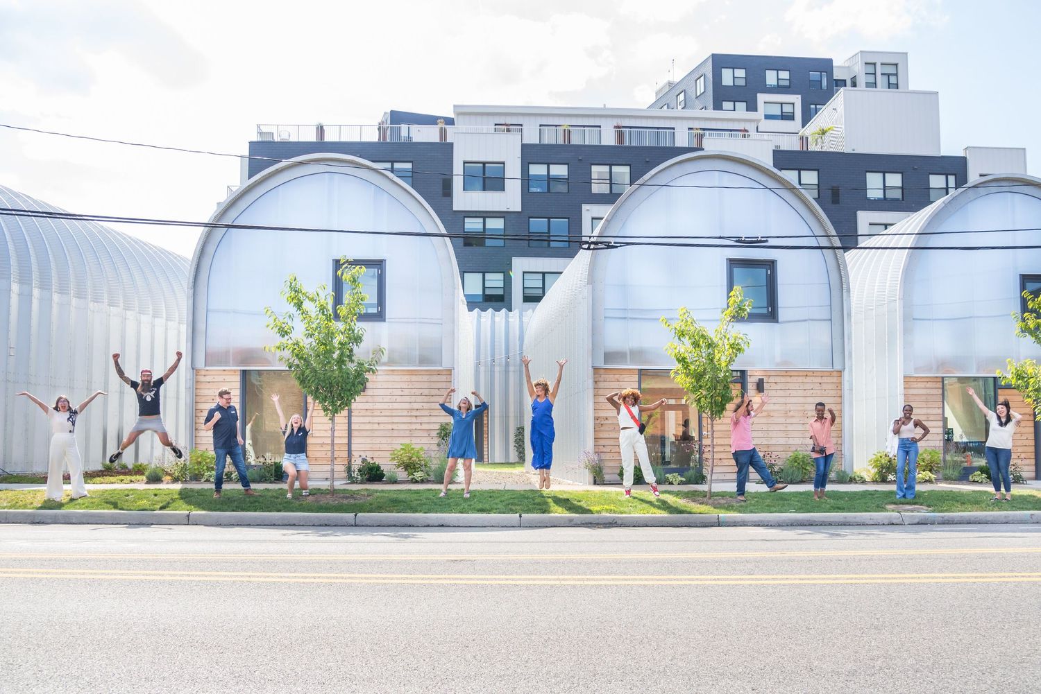People jumping in front of a modern building exterior in a panoramic sequence.